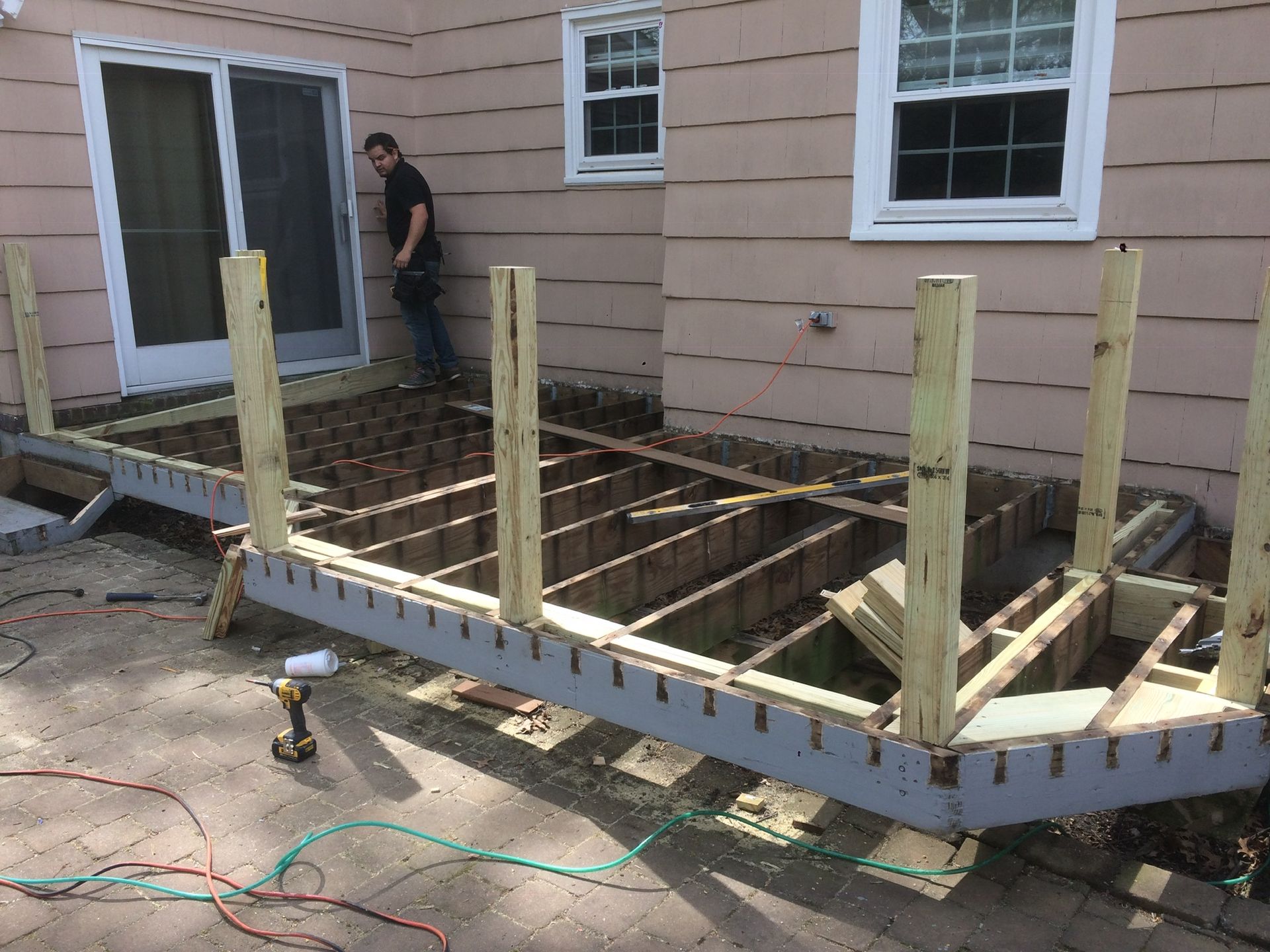 A man is working on a wooden deck in front of a house.