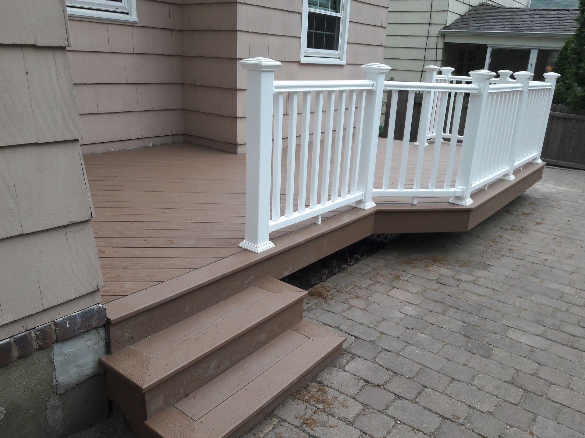 A wooden deck with stairs and a white railing