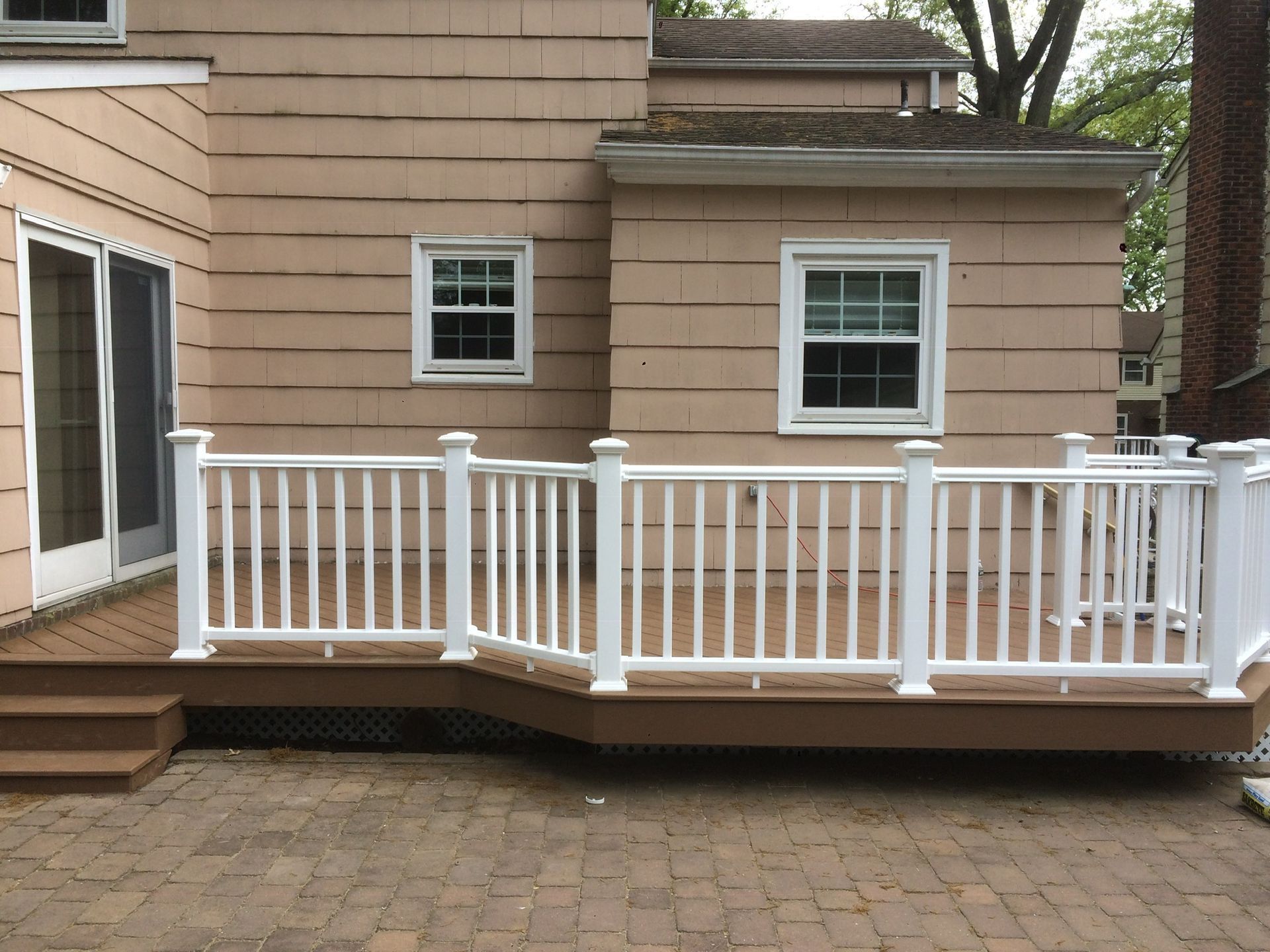 A deck with a white railing in front of a house