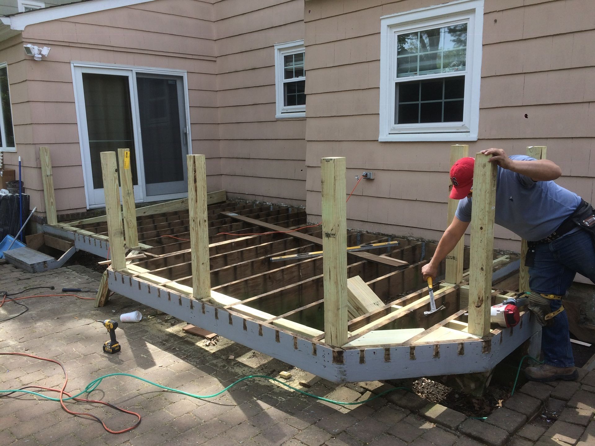 A man is working on a wooden deck in front of a house