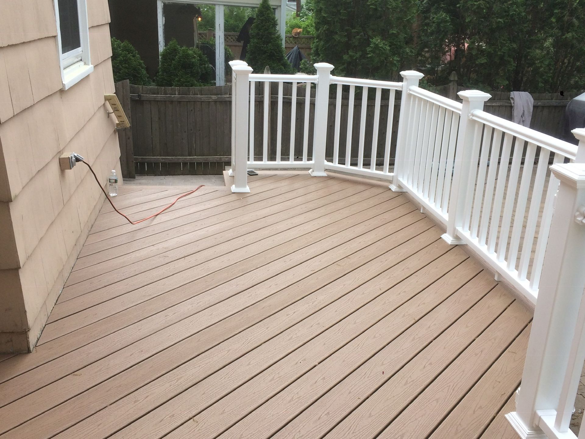 A deck with a white railing and a fence in the background