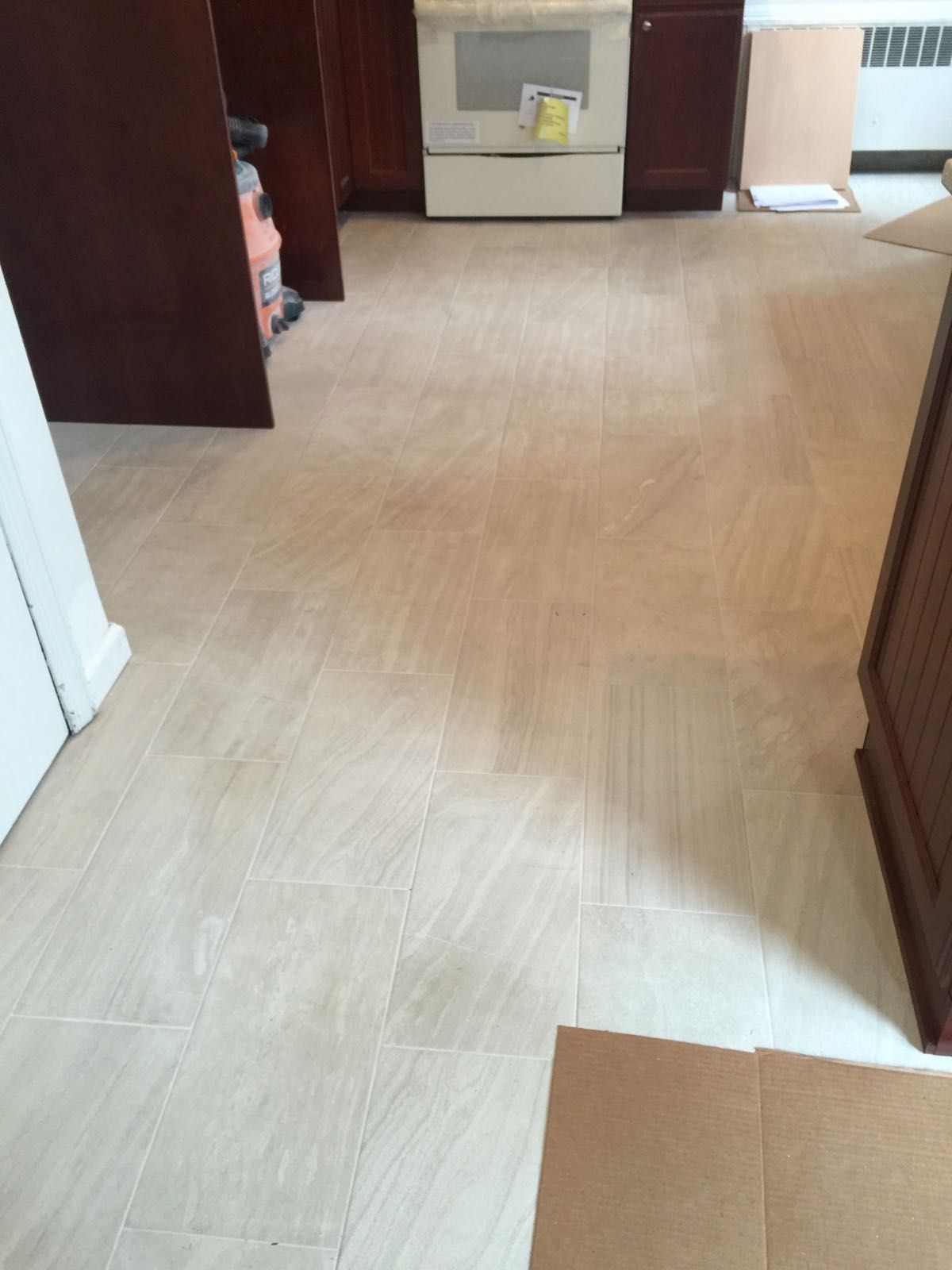 A kitchen with a tile floor and wooden cabinets