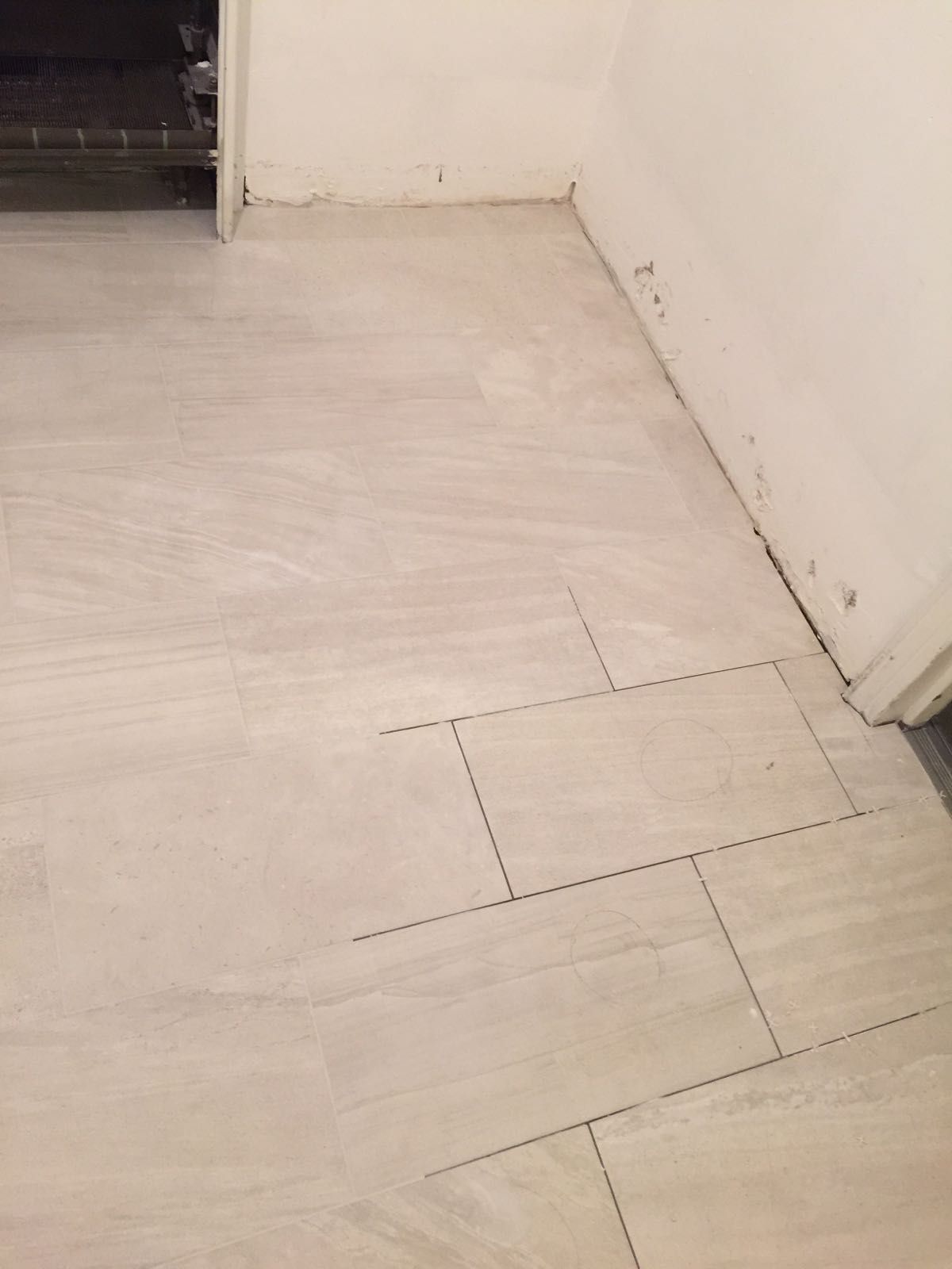 A white tile floor in a room next to a door.