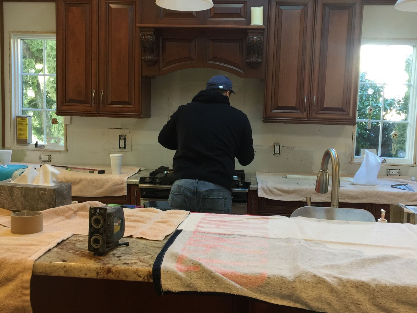 A man is working on a stove in a kitchen.