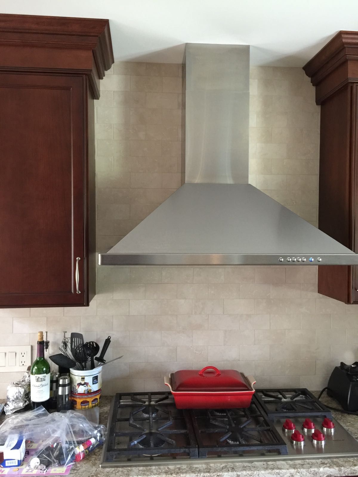 A kitchen with a stove top oven and a stainless steel hood