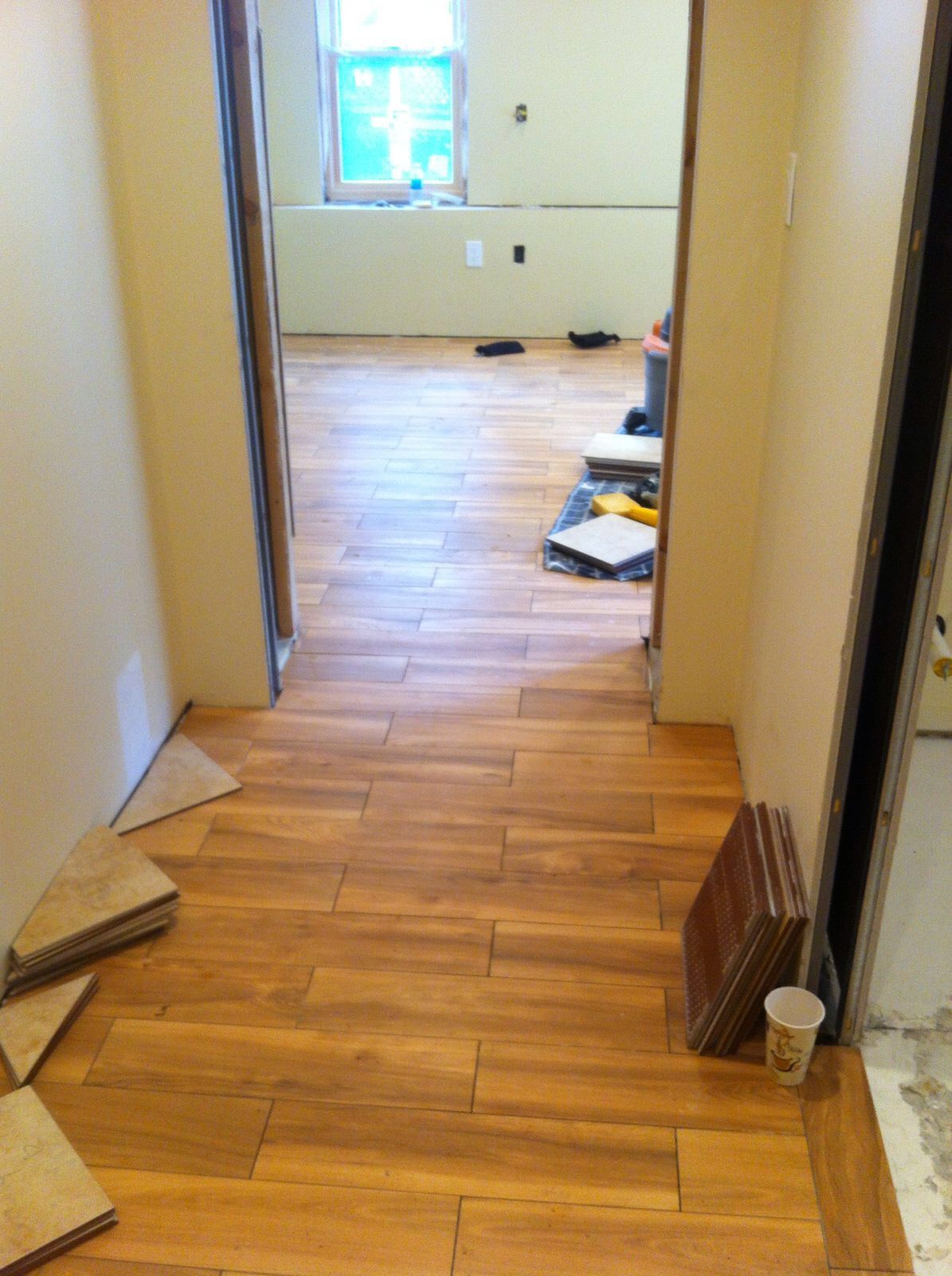 A hallway with a wooden floor and a cup on the floor