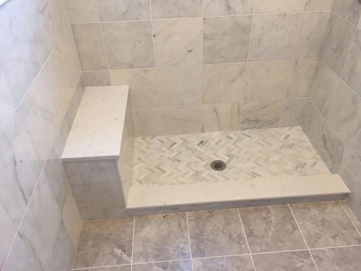 A bathroom with a walk in shower and a bench.