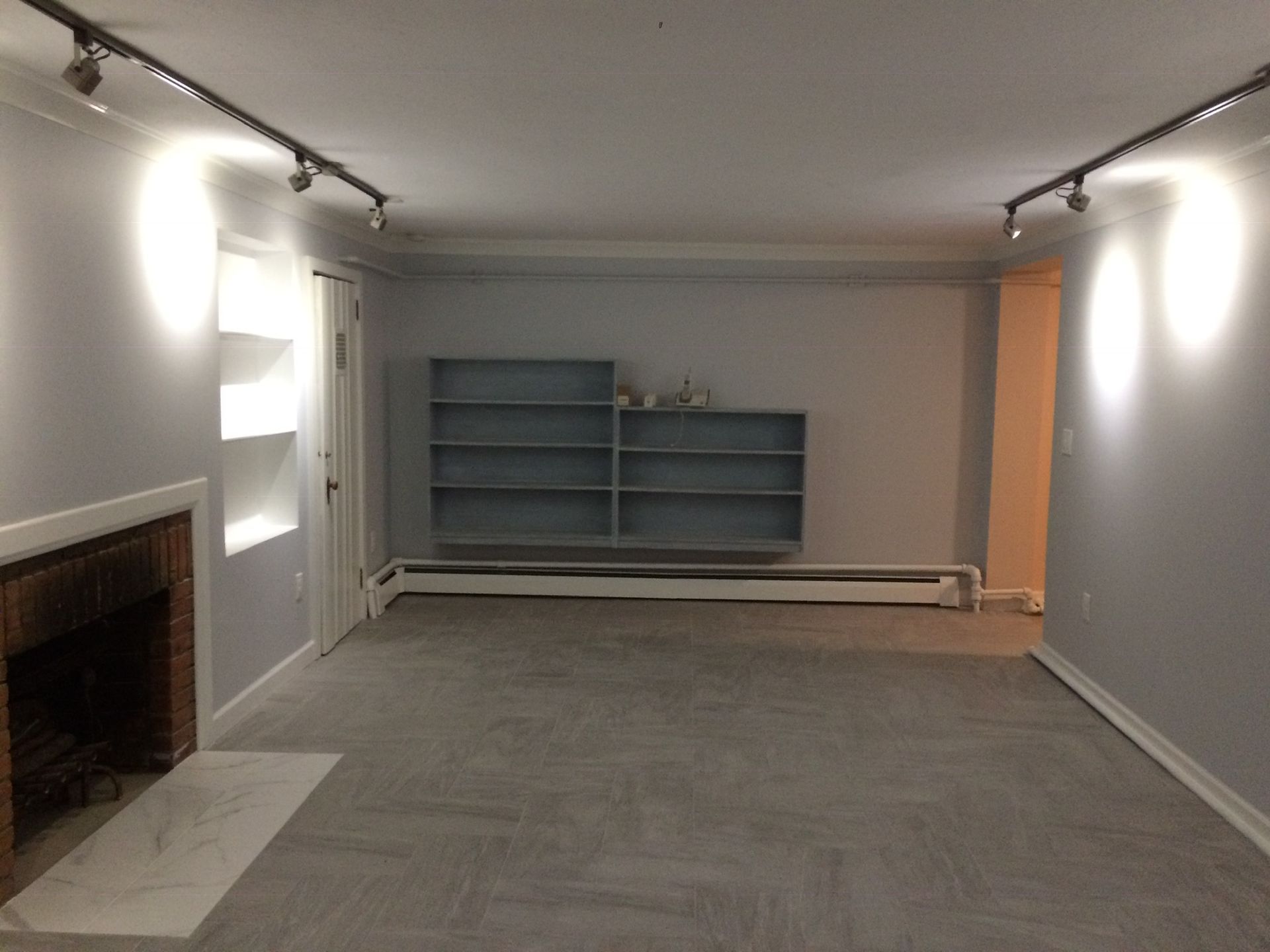 An empty living room with a fireplace and shelves