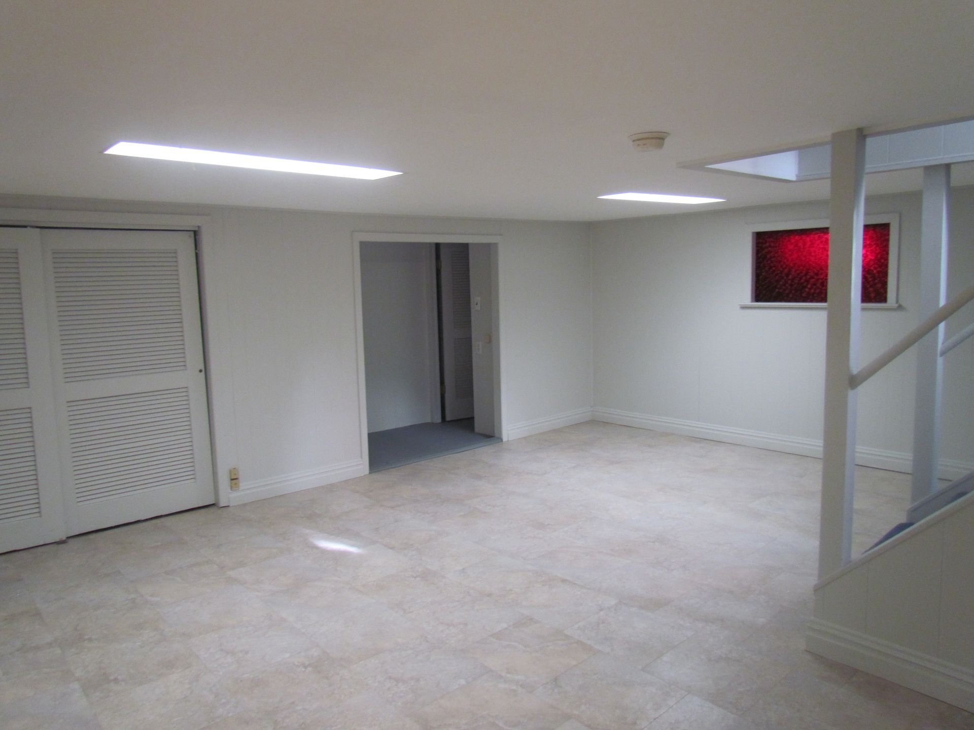 An empty basement with white walls and tile floors