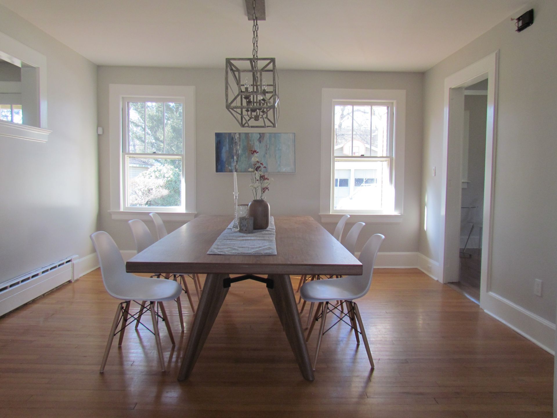 A dining room with a long table and white chairs