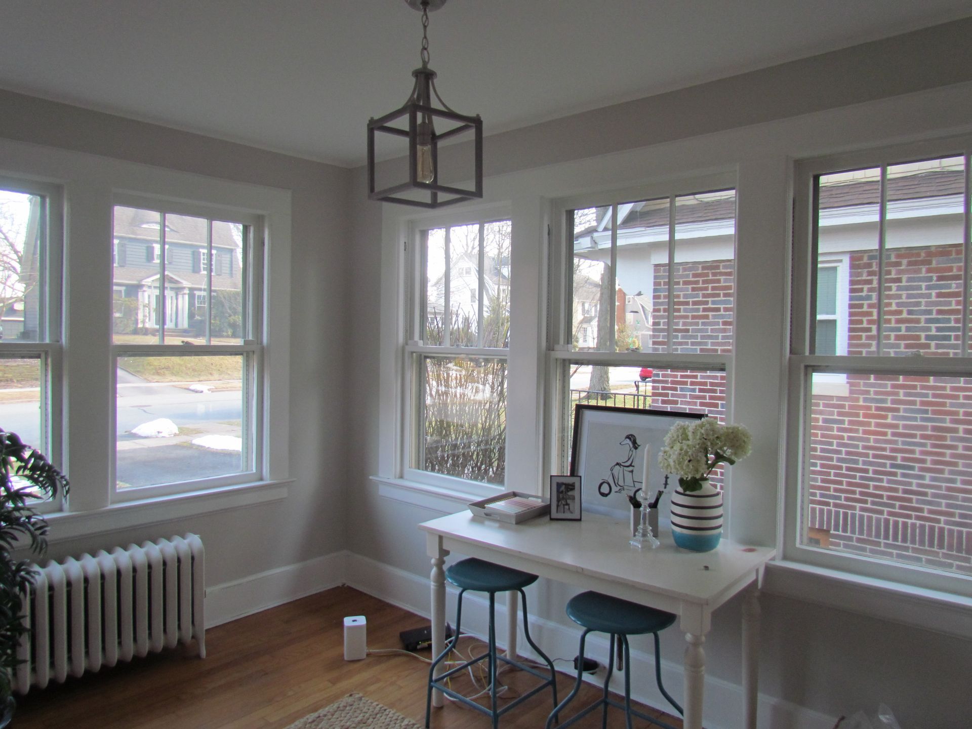 A room with a table and stools and a lot of windows.