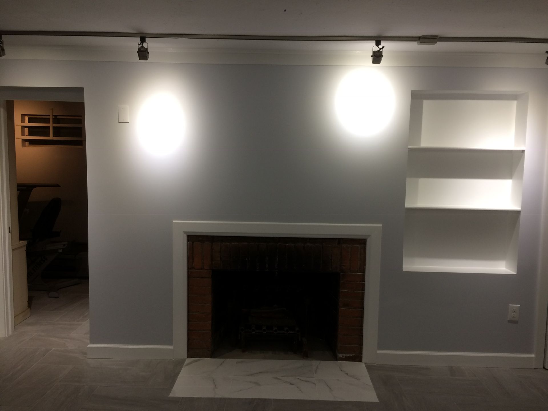 An empty living room with a fireplace and shelves