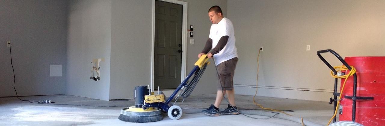 A man is using a machine to polish the floor in a garage.