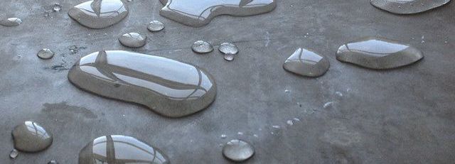 A close up of water drops on a concrete surface.