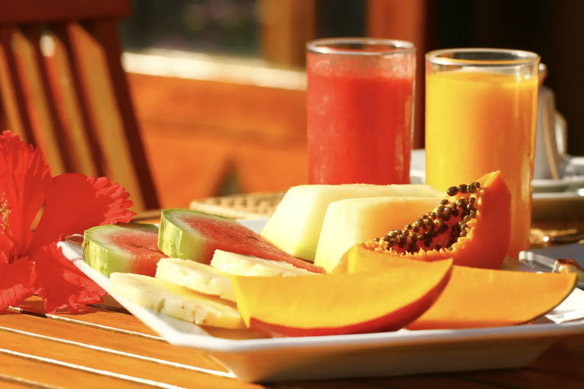 Um prato de frutas e dois copos de suco de laranja sobre uma mesa