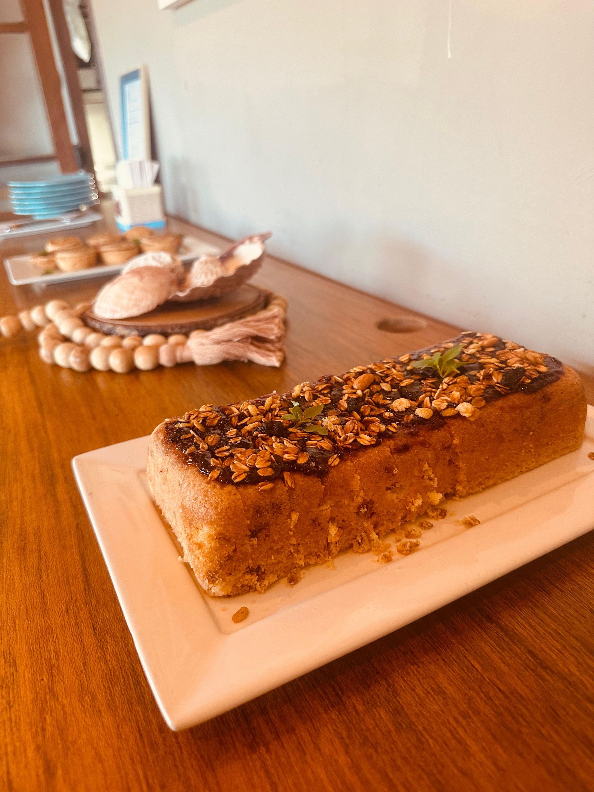 Um pedaço de bolo está em um prato branco sobre uma mesa de madeira.