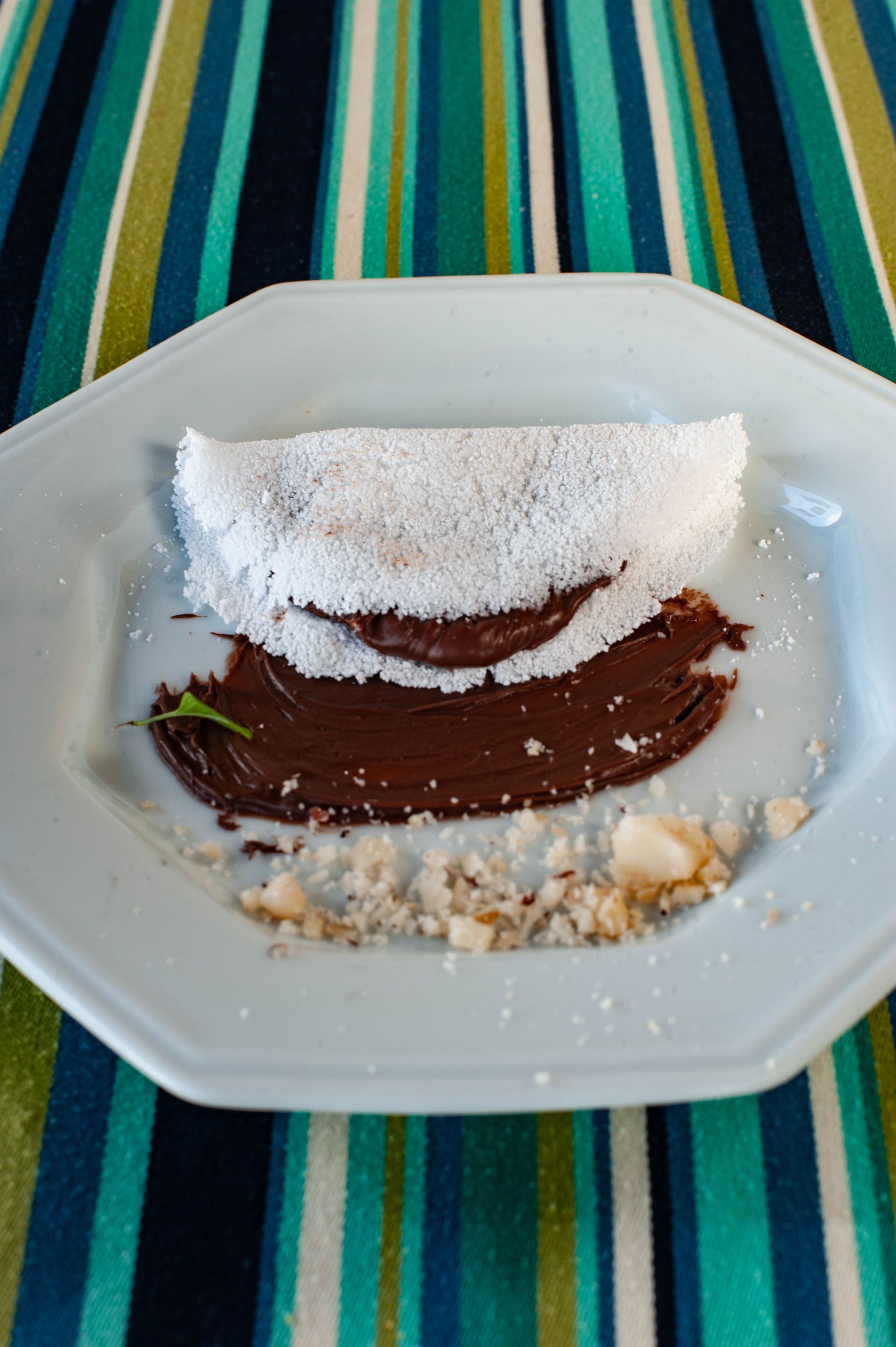 Um prato branco coberto com um pedaço de comida e calda de chocolate.