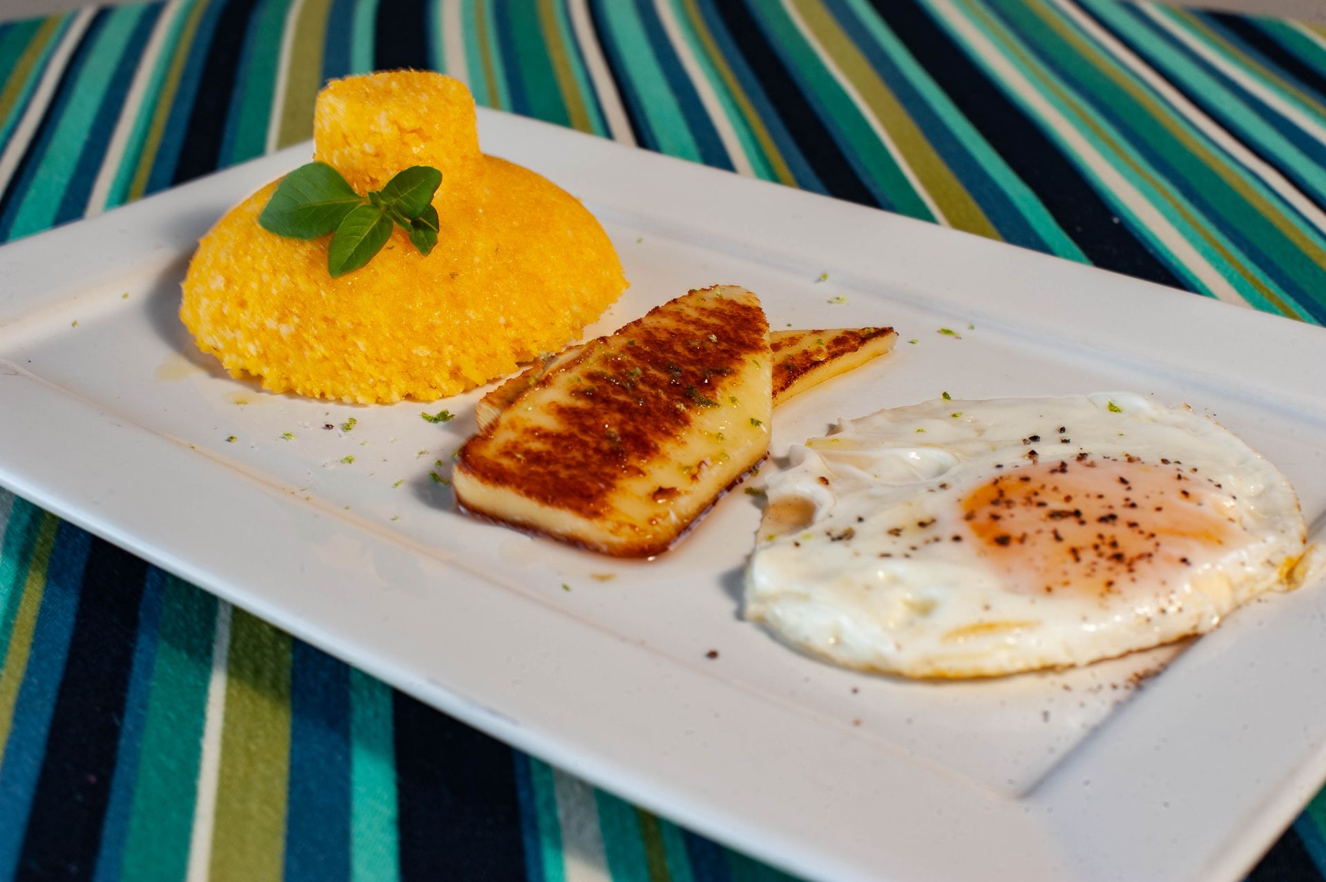 Um prato branco coberto com um ovo frito e um pedaço de queijo.