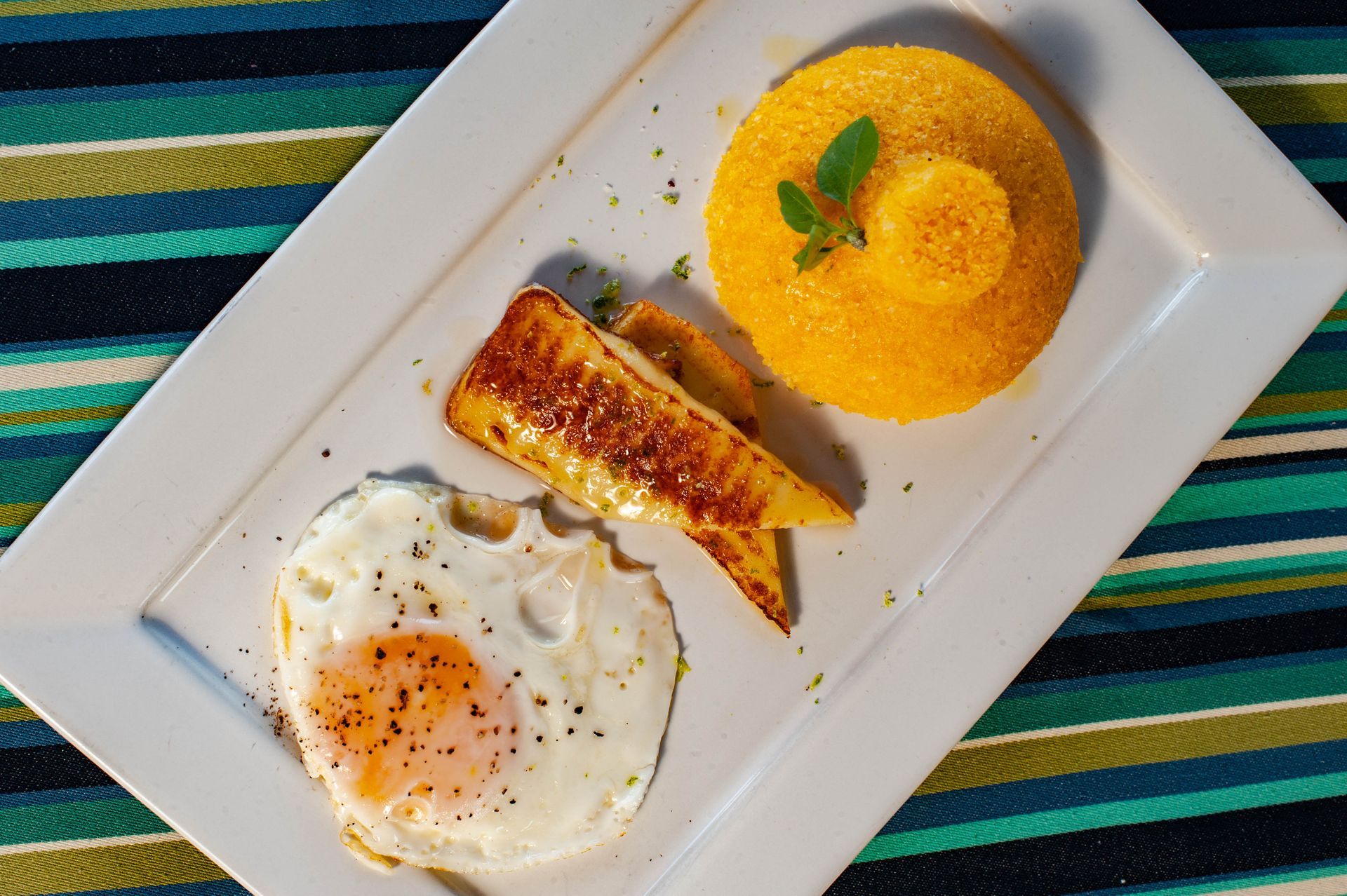 Um prato branco coberto com um ovo frito e um pedaço de pão