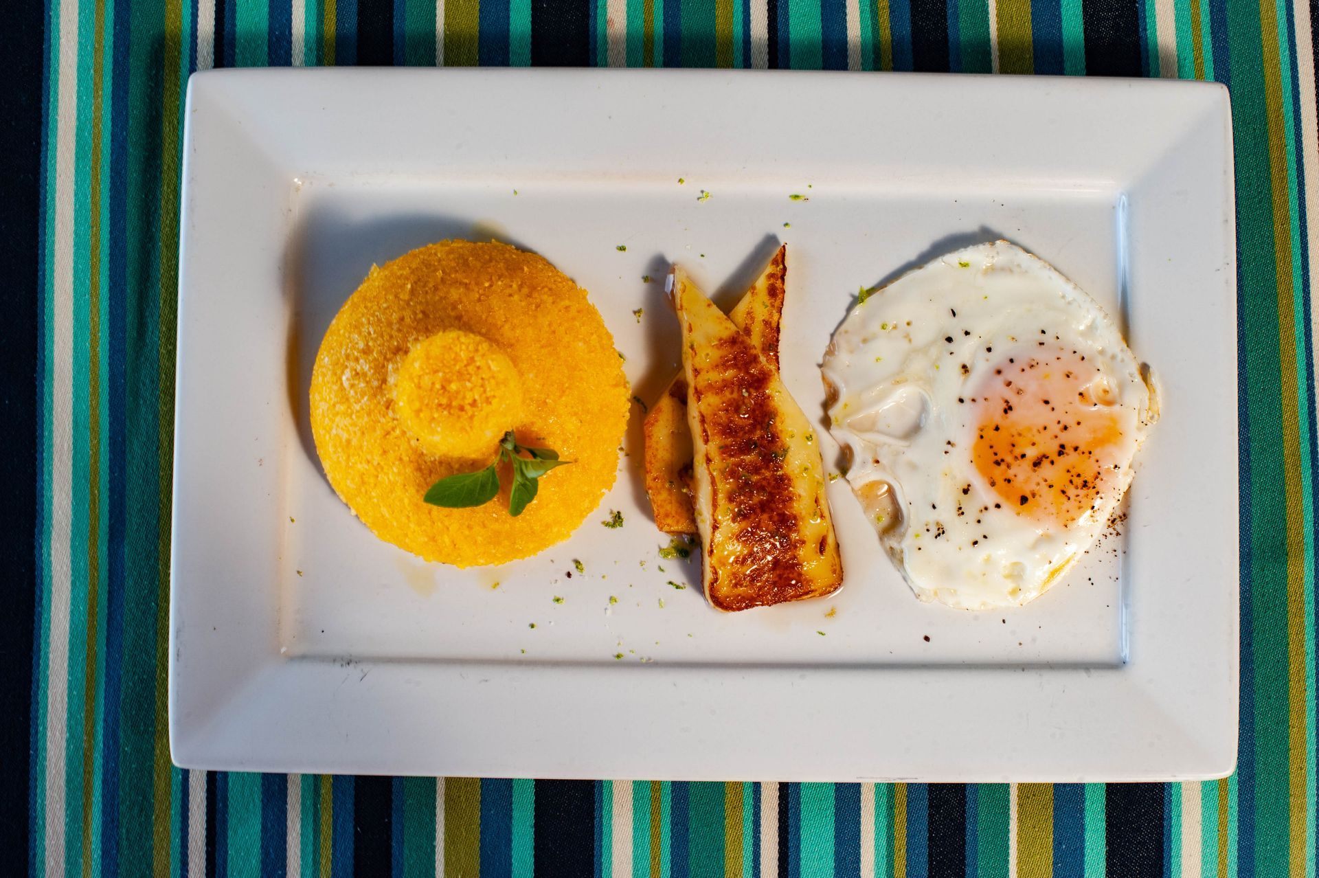 Um prato branco coberto com um ovo frito e um pedaço de pão.