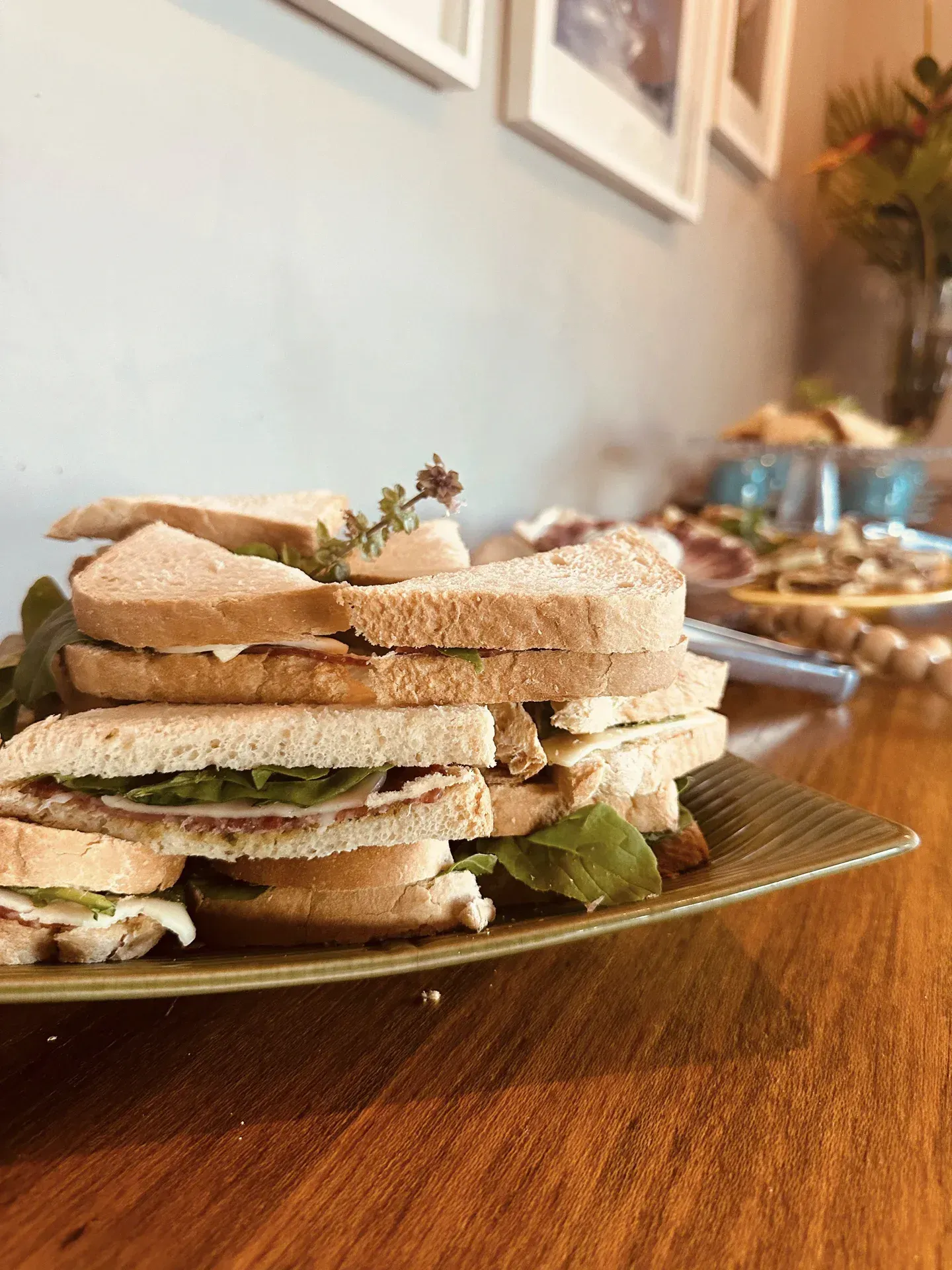 Uma pilha de sanduíches em um prato sobre uma mesa de madeira.