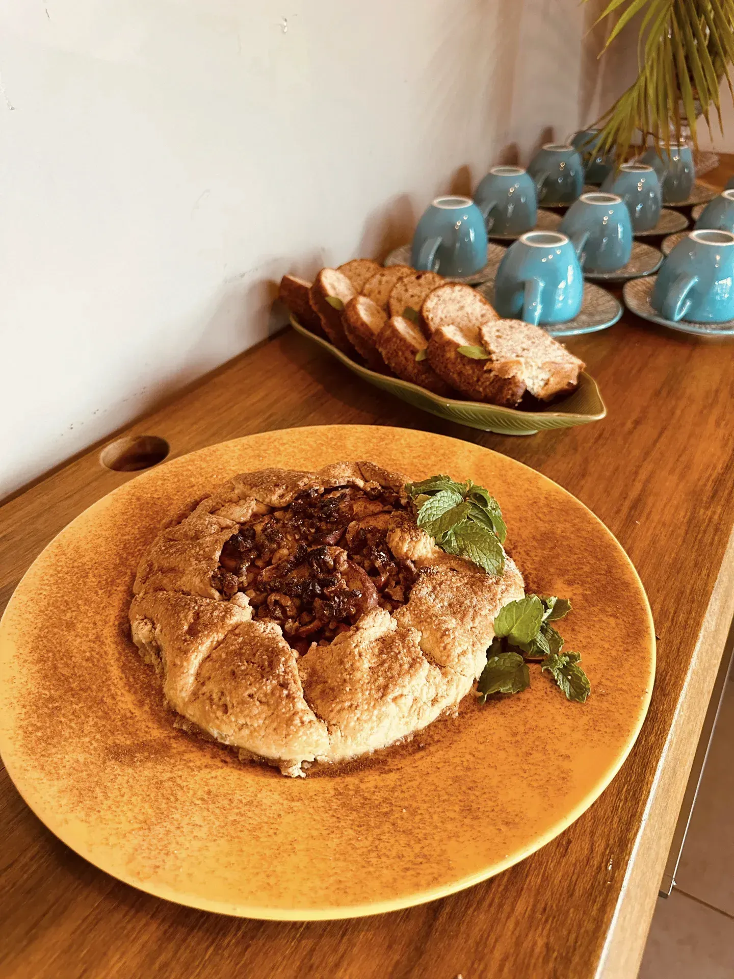 Um prato de comida está sobre uma mesa de madeira ao lado de uma tigela de pão.
