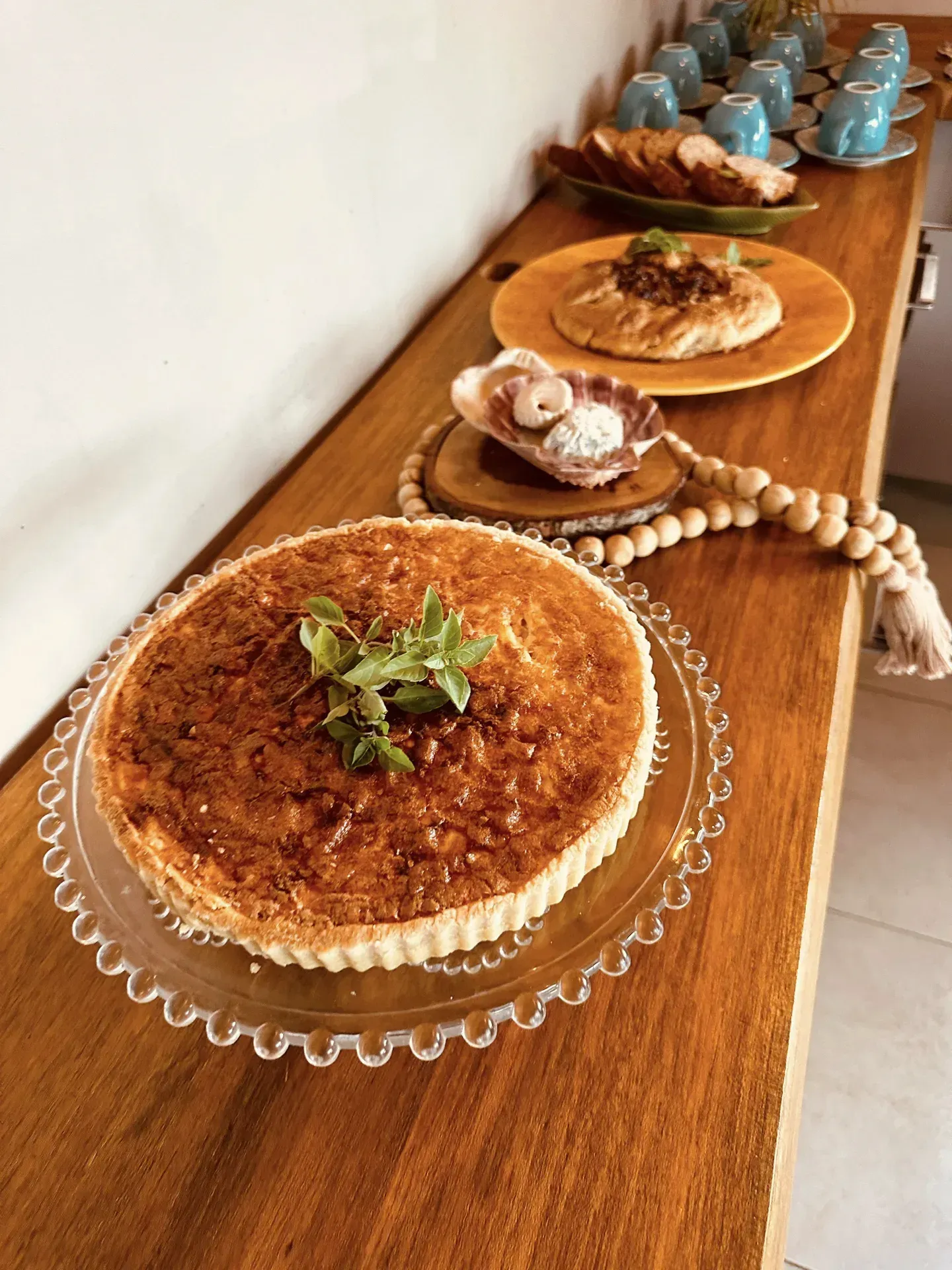 Uma torta está sobre um prato de vidro em uma mesa de madeira.