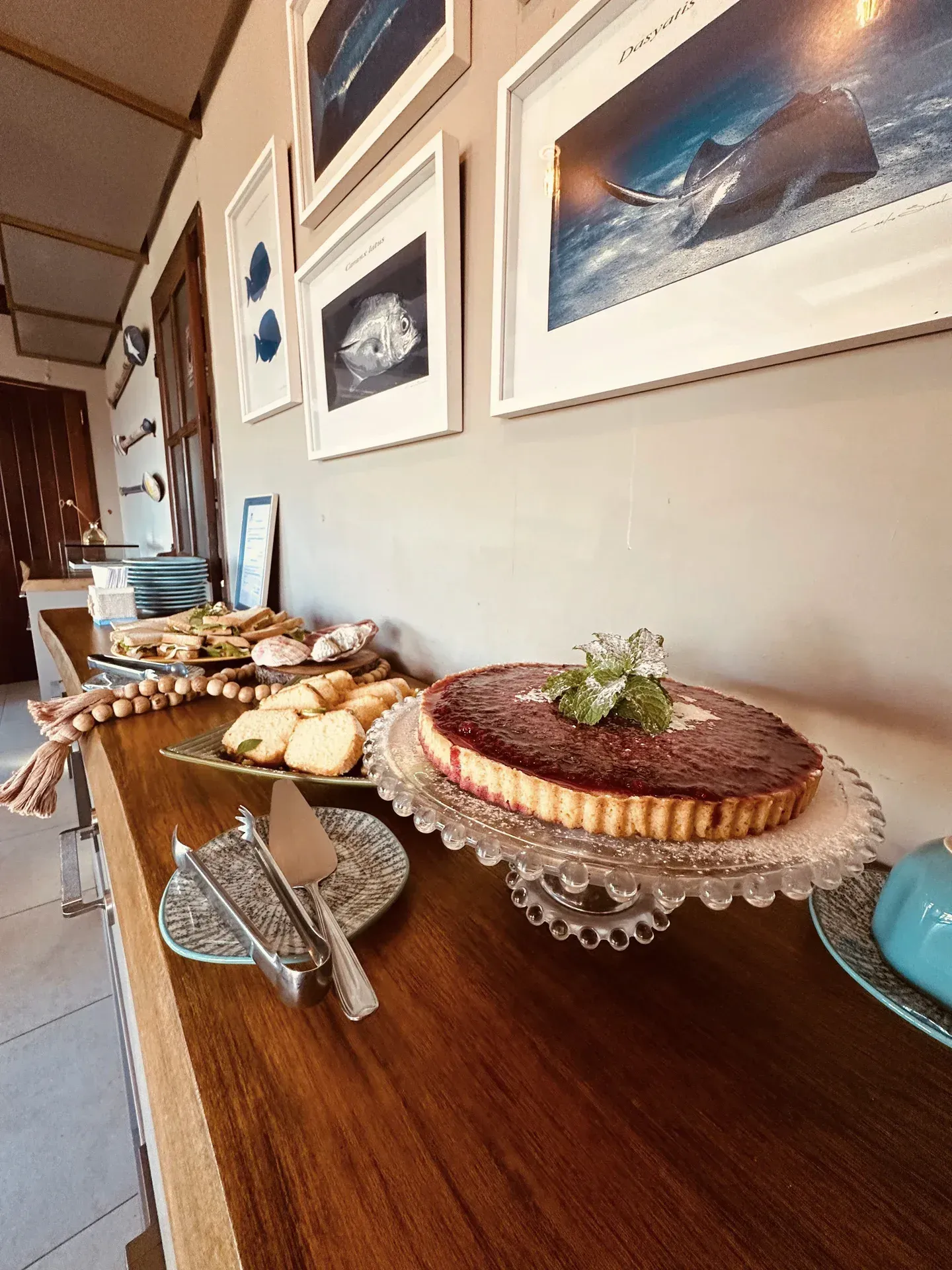 Uma mesa de madeira coberta com pratos de comida e um bolo em um prato de vidro.