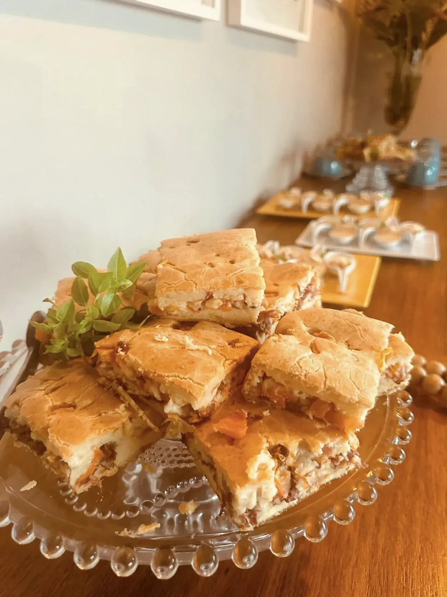 Um prato de vidro coberto com fatias de torta sobre uma mesa de madeira.
