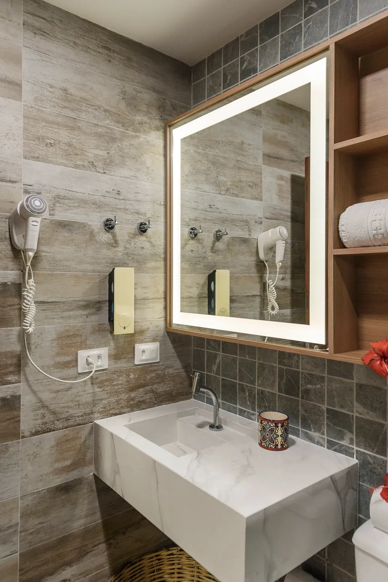 Um banheiro com pia, espelho e secador de cabelo.