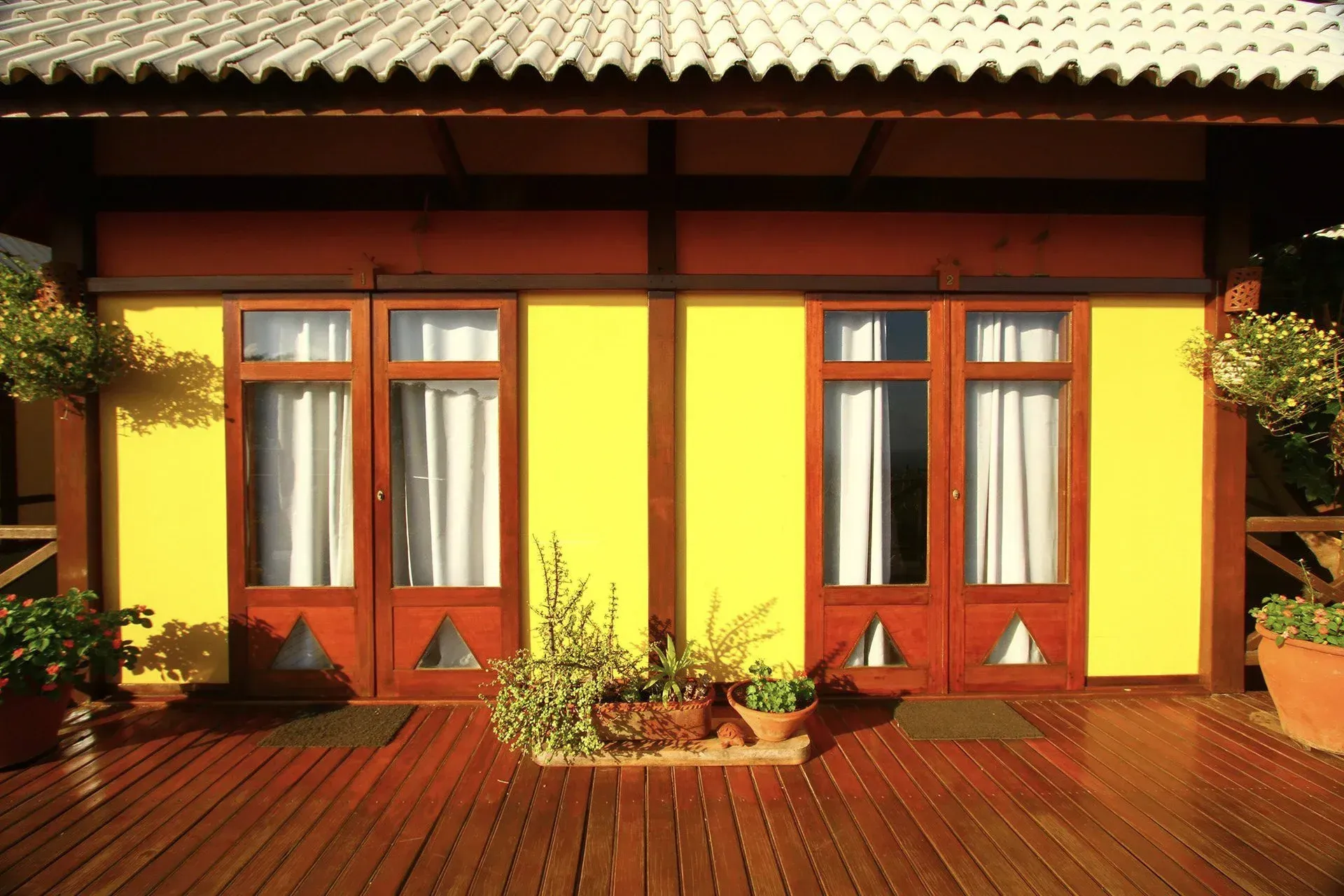 Uma casa amarela com um deck de madeira na frente