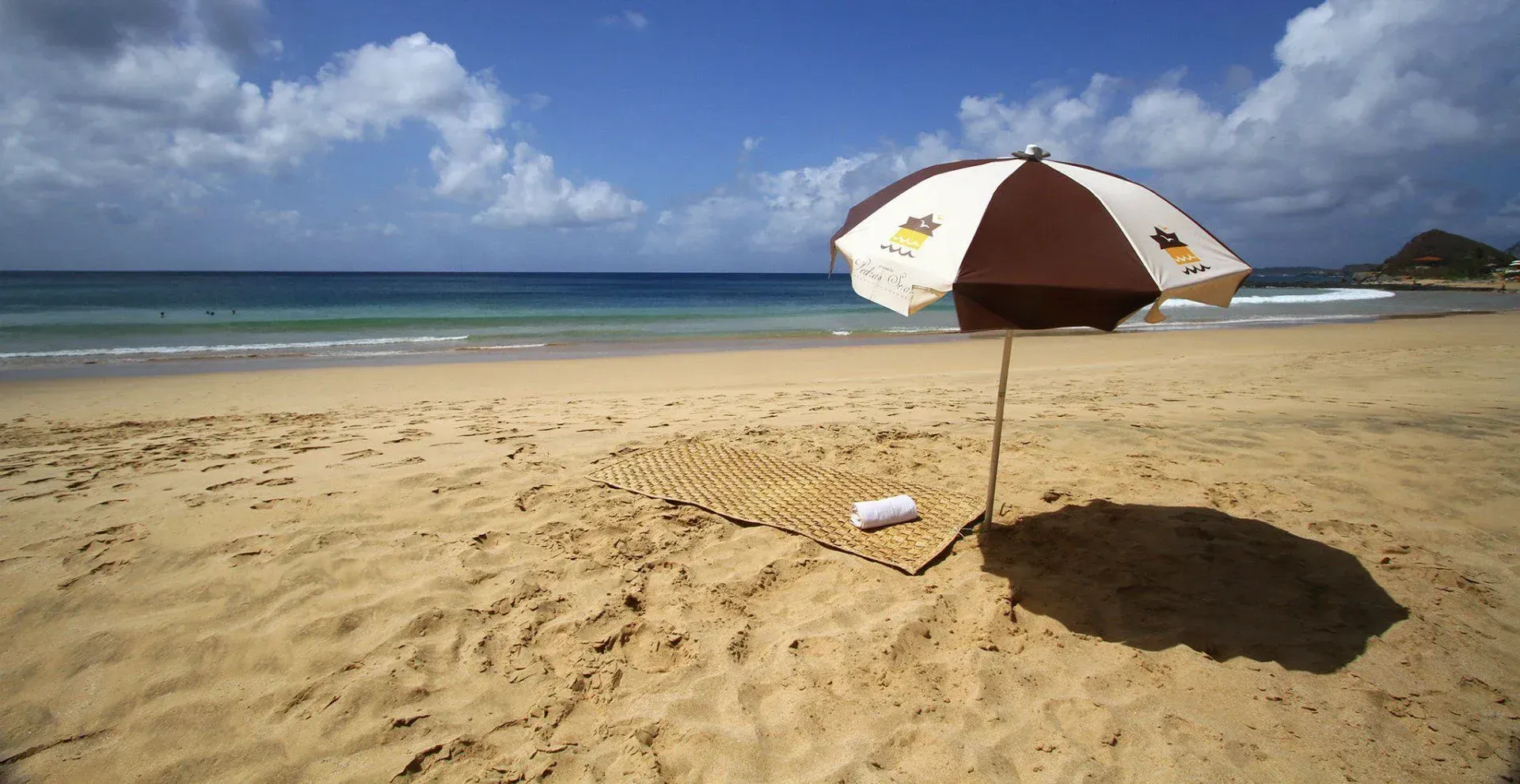 Um guarda-chuva marrom e branco em uma praia arenosa