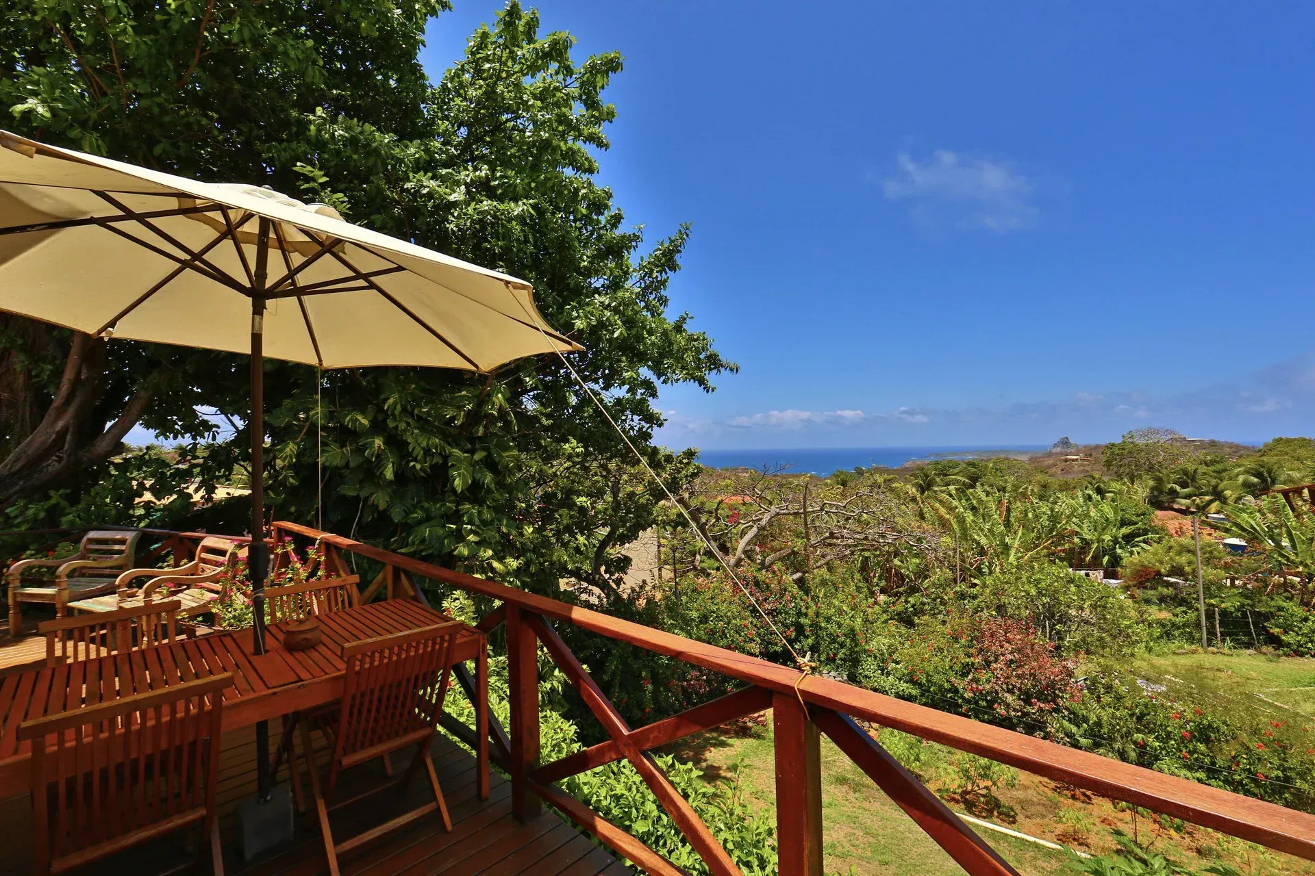 Um deck com mesa e cadeiras e guarda-sol com vista para o oceano