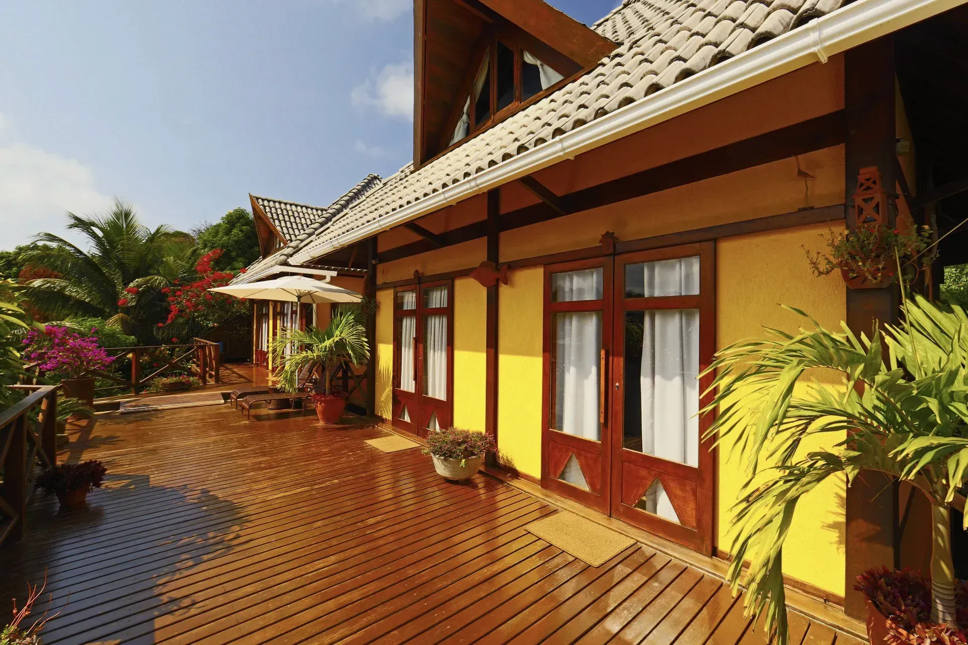 Uma casa amarela com um deck de madeira na frente