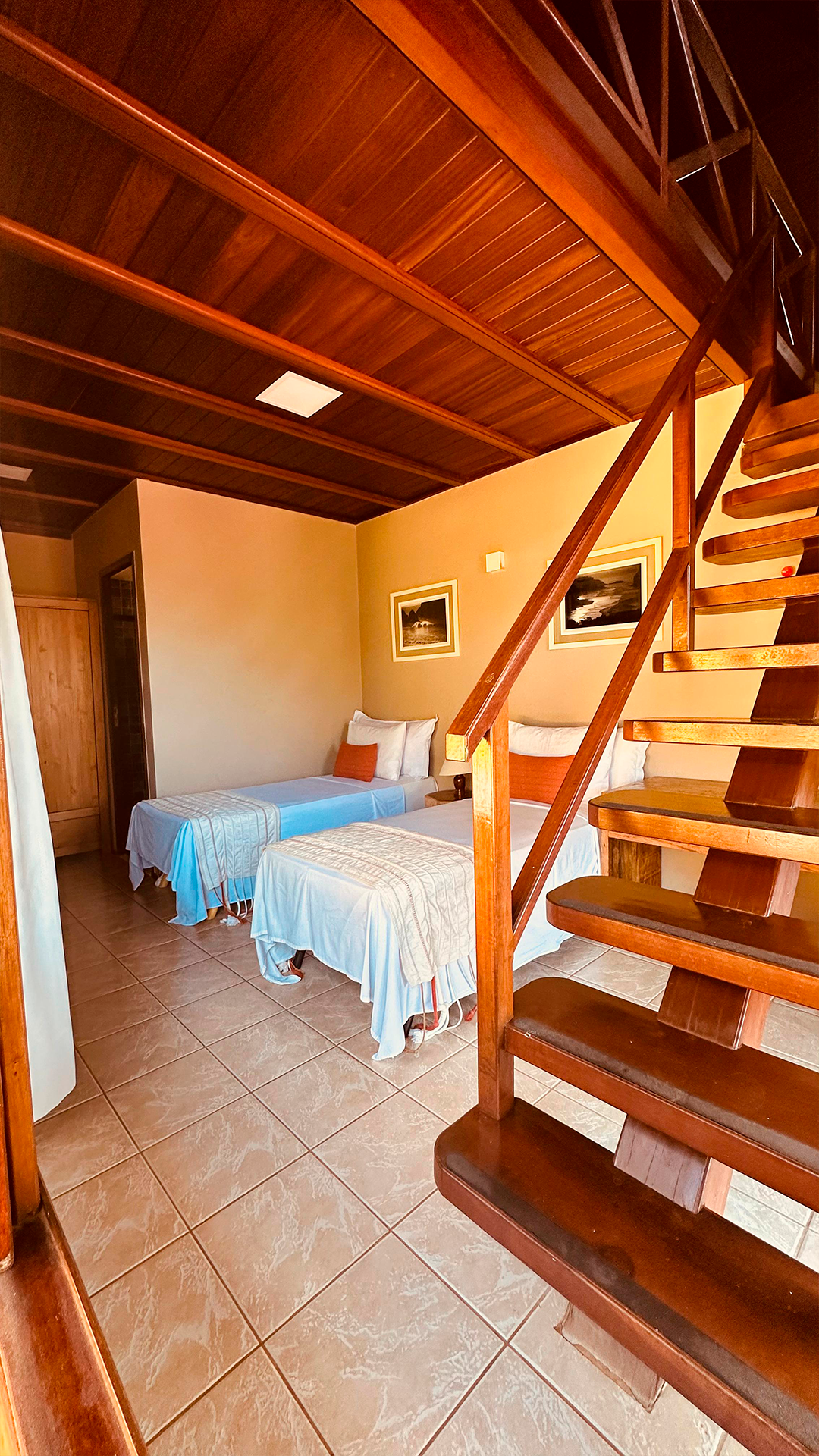 Um quarto com três camas e escadas que levam ao segundo andar.