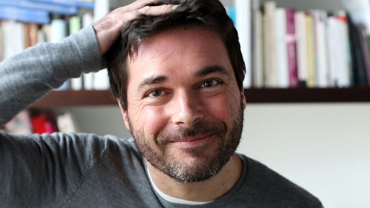 Saverio Tommasi, scrittore, blogger, giornalista sorride e si tocca la testa.