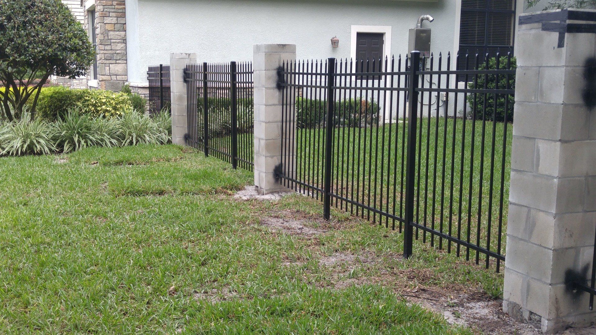 a black fence surrounds a lush green yard in front of a house .