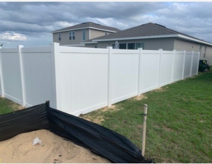 a white fence is in the backyard of a house .