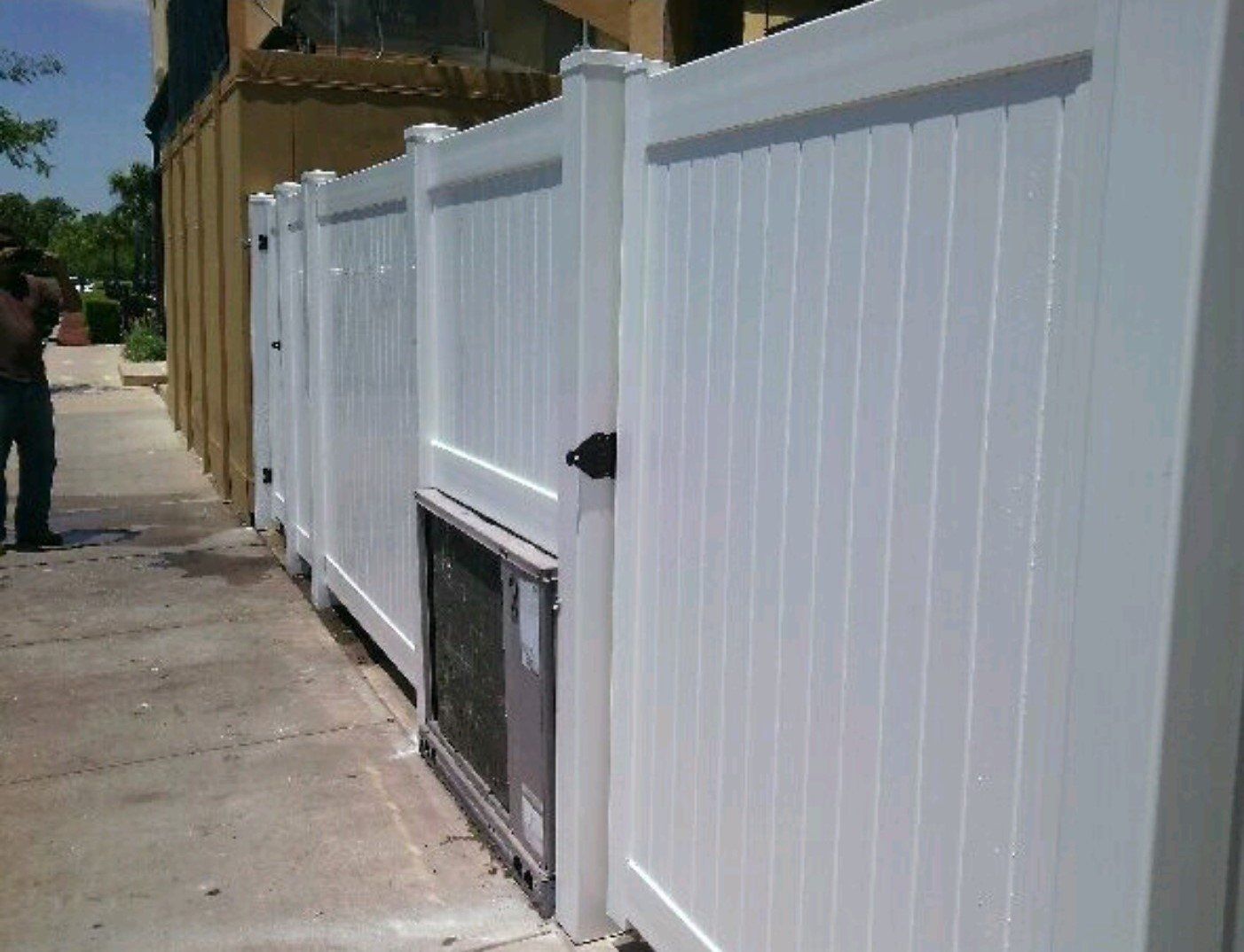a man is standing next to a white fence