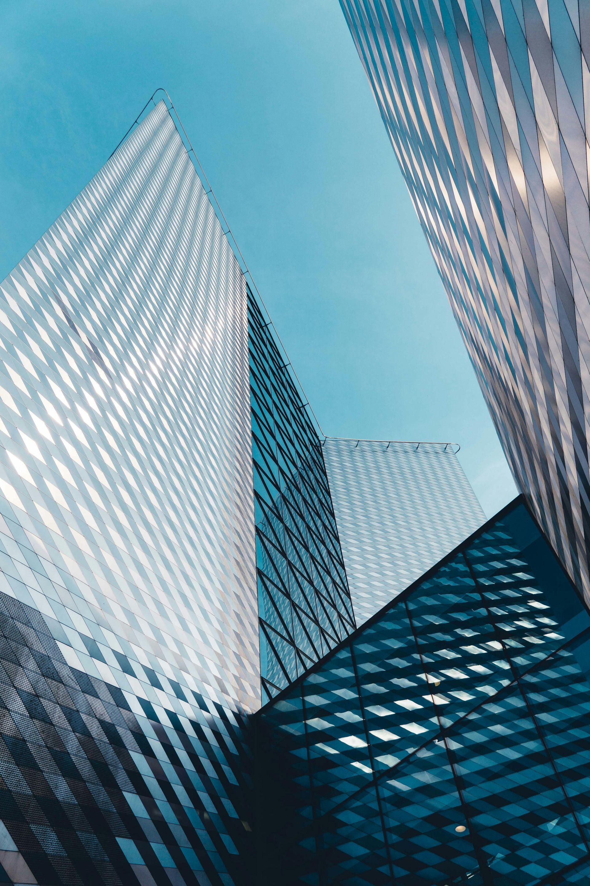 Skyscrapers against a bright blue sky, angled upward with reflections in windows.