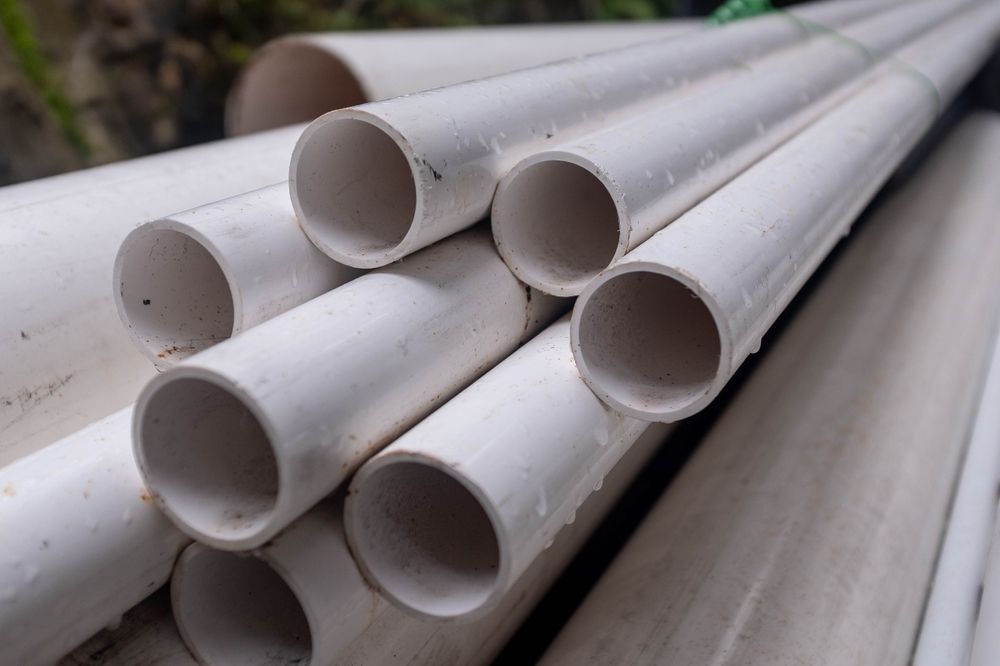 White PVC pipes stacked together, outdoors.