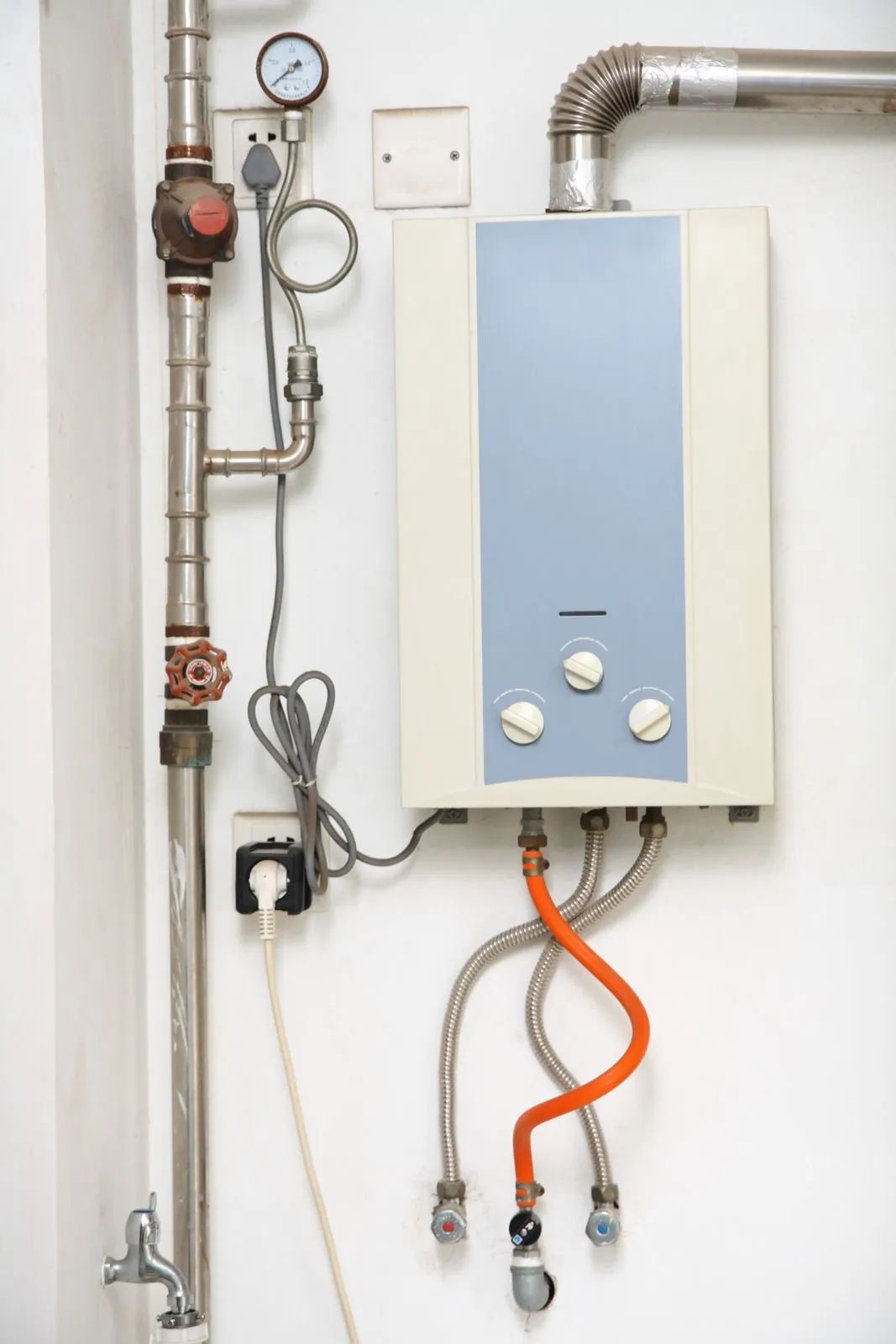 Wall-mounted boiler with pipes, gauges, and hoses in a utility room