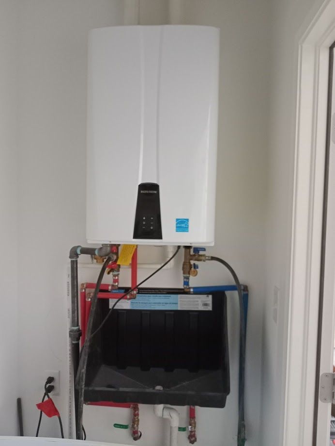 A white, wall-mounted tankless water heater above a utility sink with connected pipes.