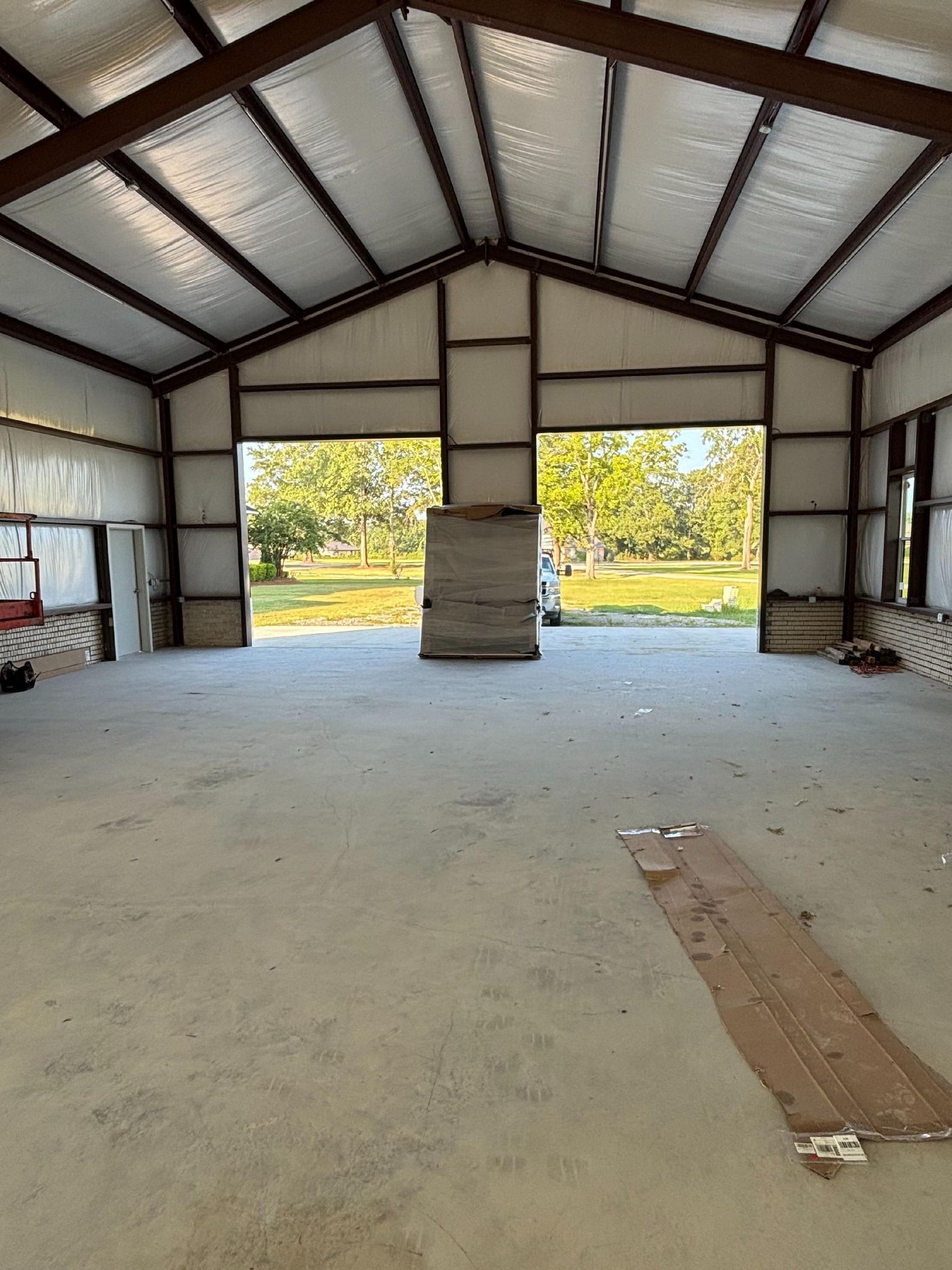 Interior of an empty metal building with two open doorways facing the outdoors.