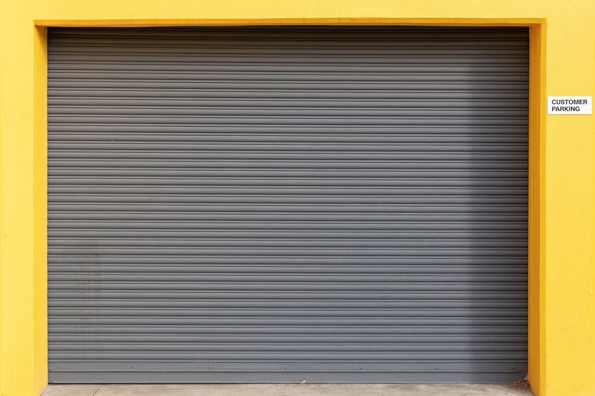 Gray rolling metal door set in a yellow frame.