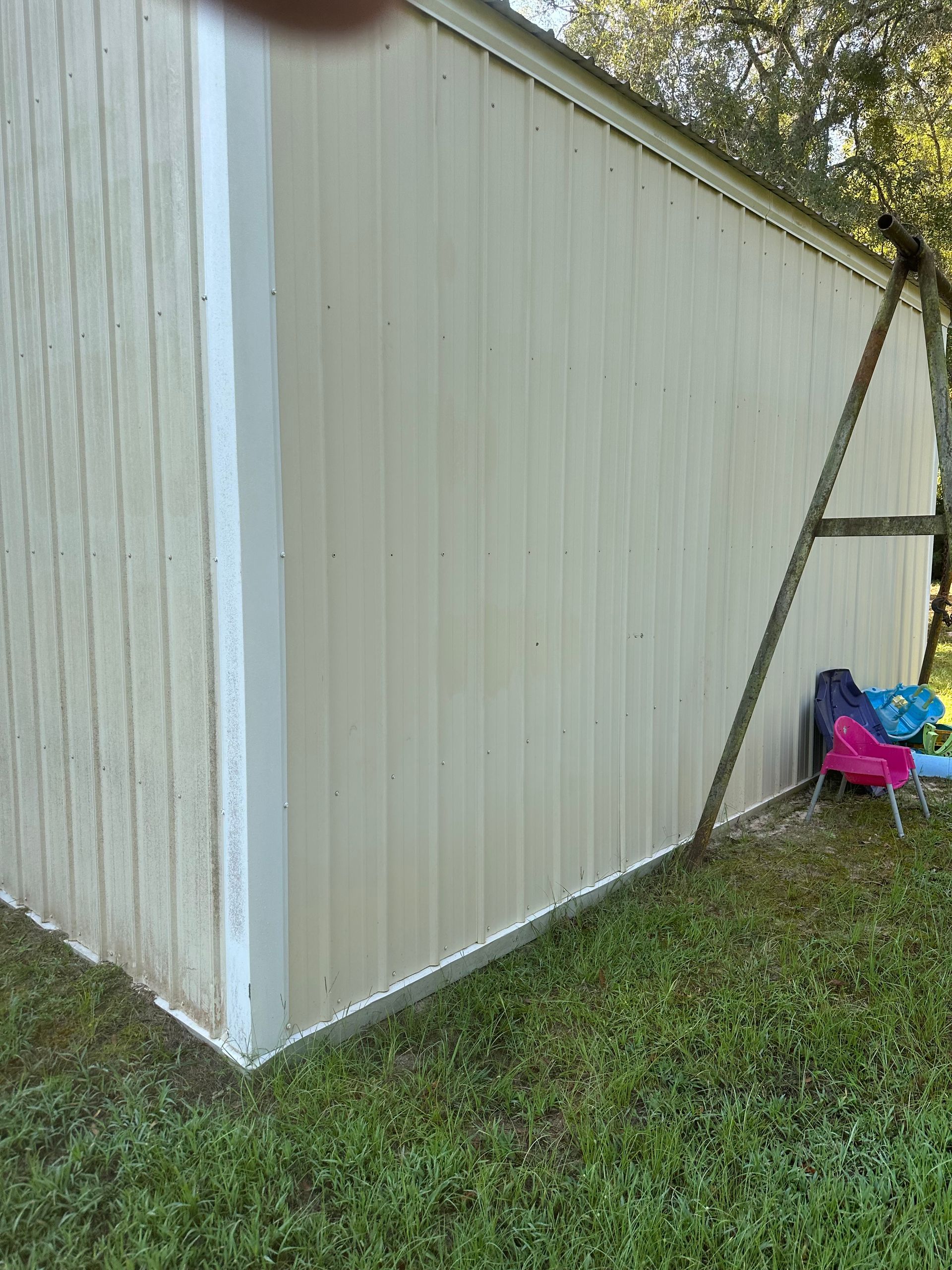 Tan metal shed with white trim, set on green grass.