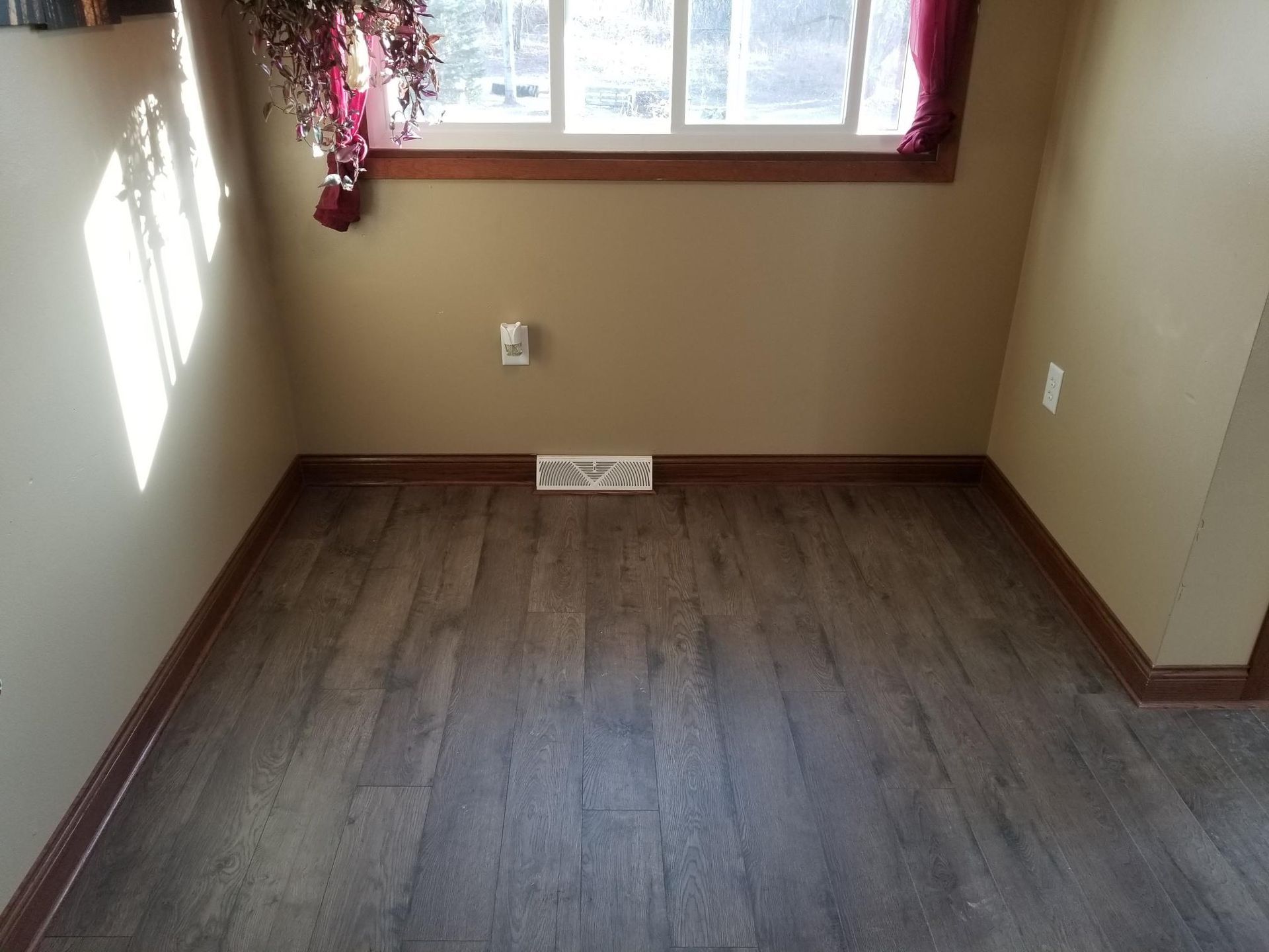 An empty room with hardwood floors and a window.