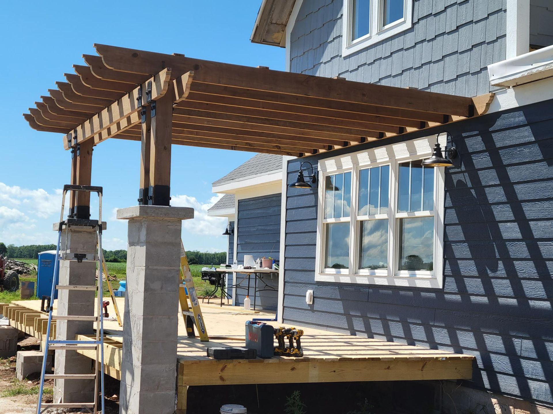 A wooden pergola is being built on the side of a house.