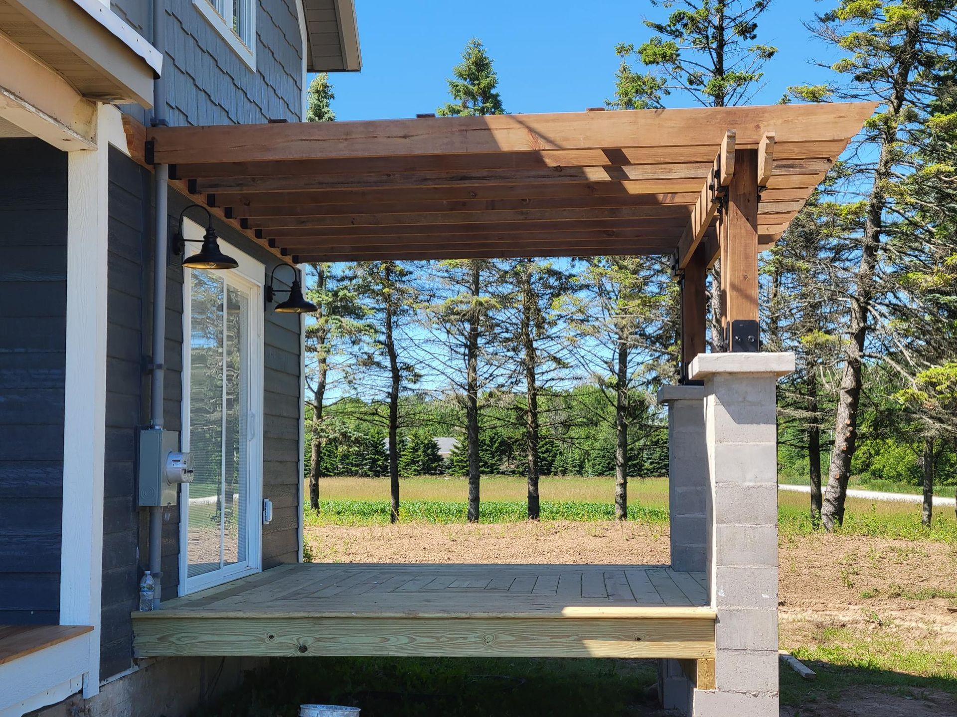 A wooden deck with a pergola attached to the side of a house.