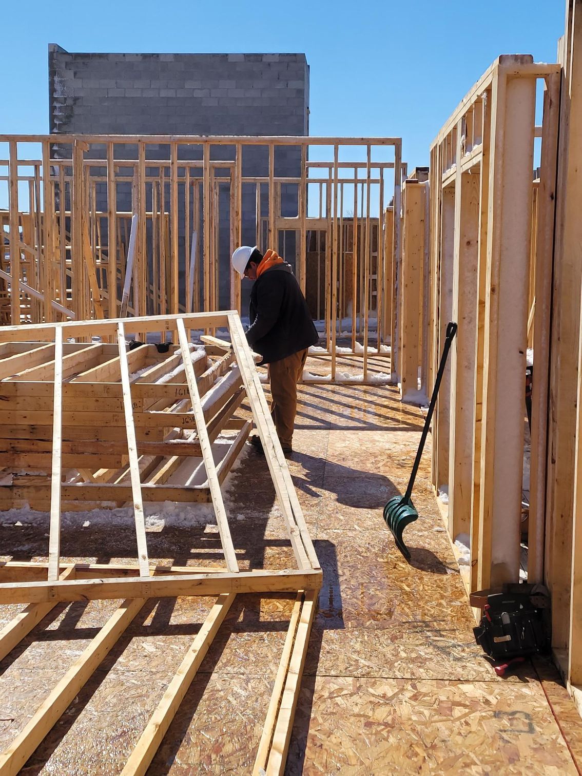 A man is working on a wooden frame of a house.